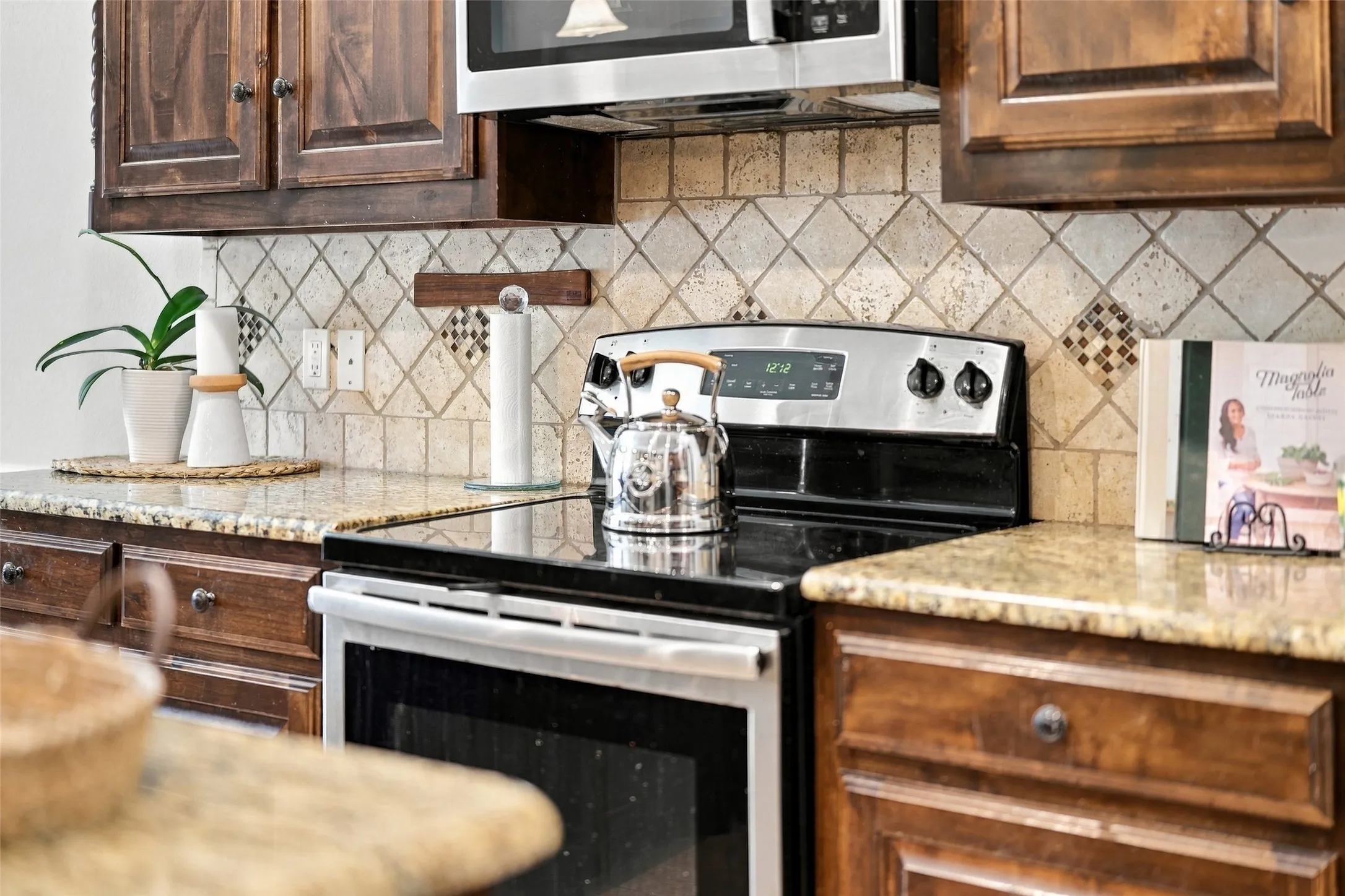 Kitchen Detail: Stainless steel cooking appliances, granite countertops, and a decorative tile backsplash complement the warm wood cabinetry.