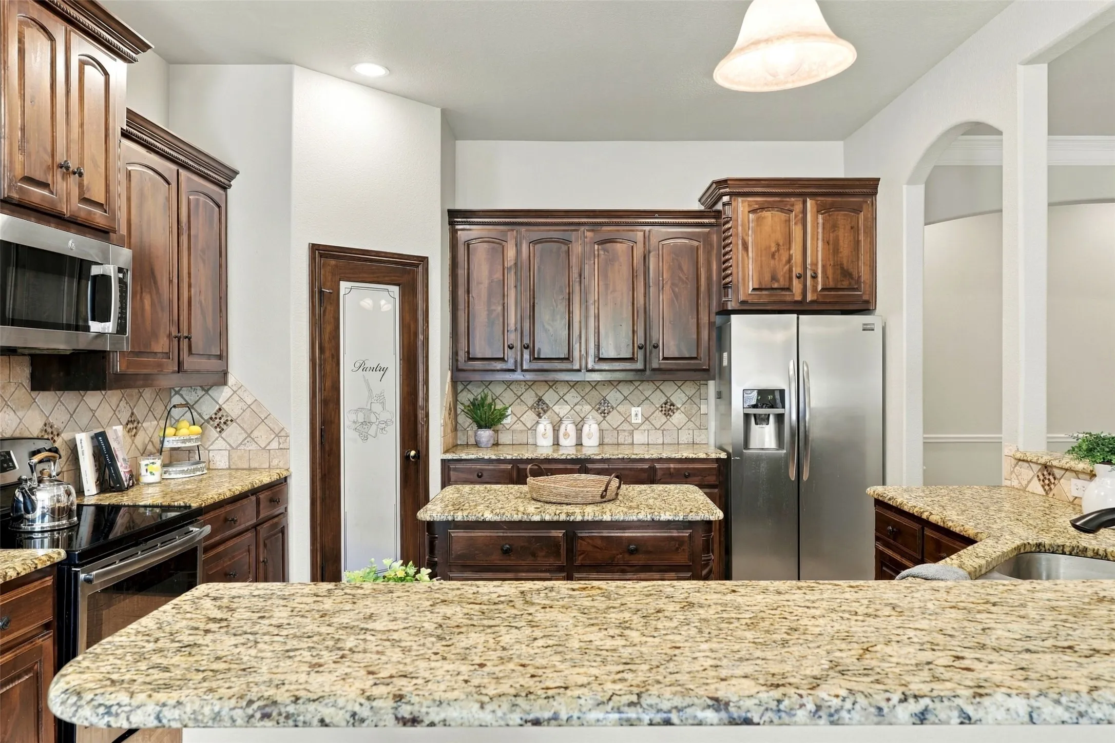 Kitchen: Rich wood cabinetry, a granite-topped center island, stainless steel appliances, and a dedicated pantry provide attractive finishes and practical storage.