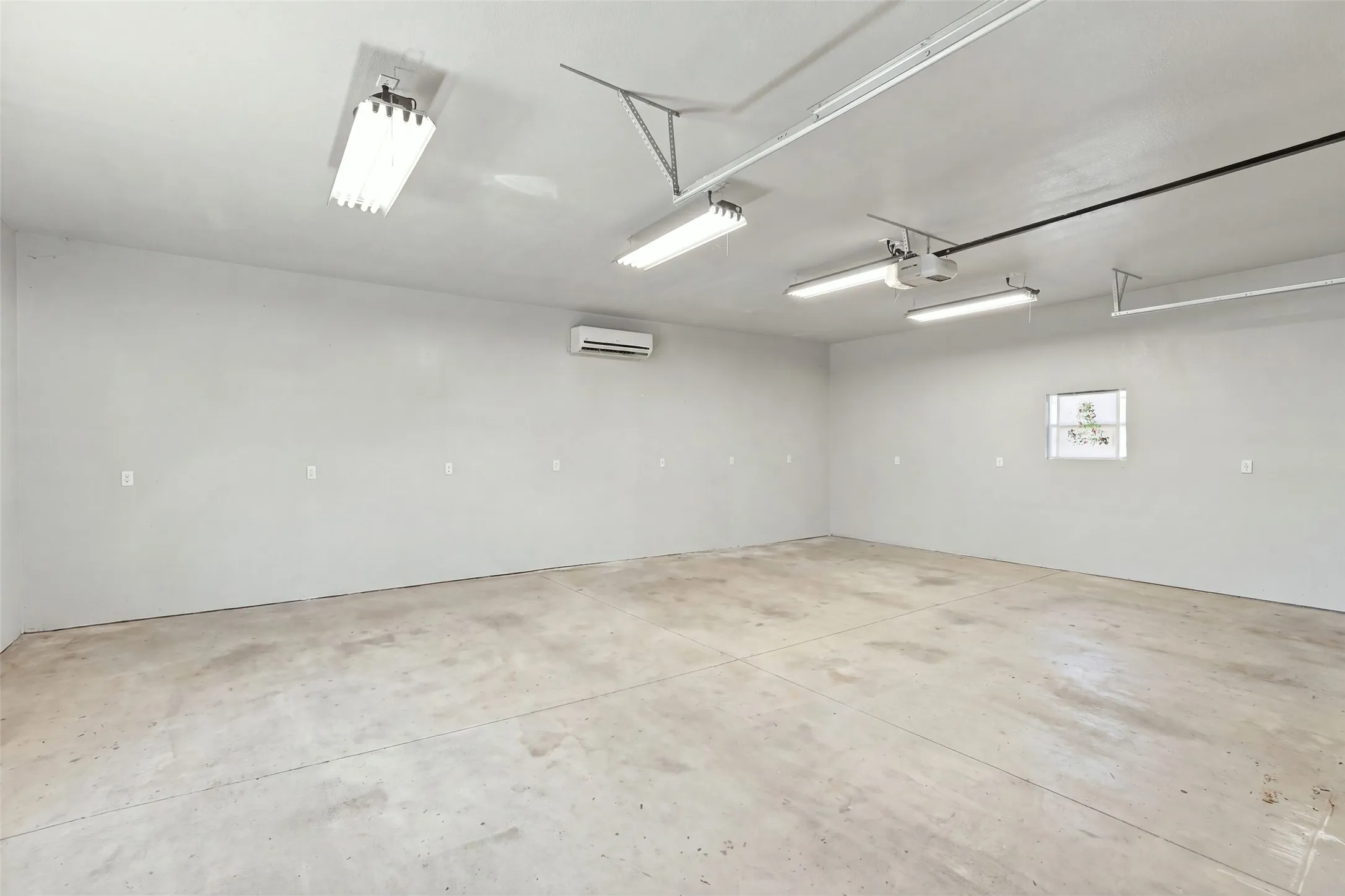 Workshop: Spacious workshop offers an open layout, concrete flooring, overhead lighting, and a wall-mounted mini-split climate control system.
