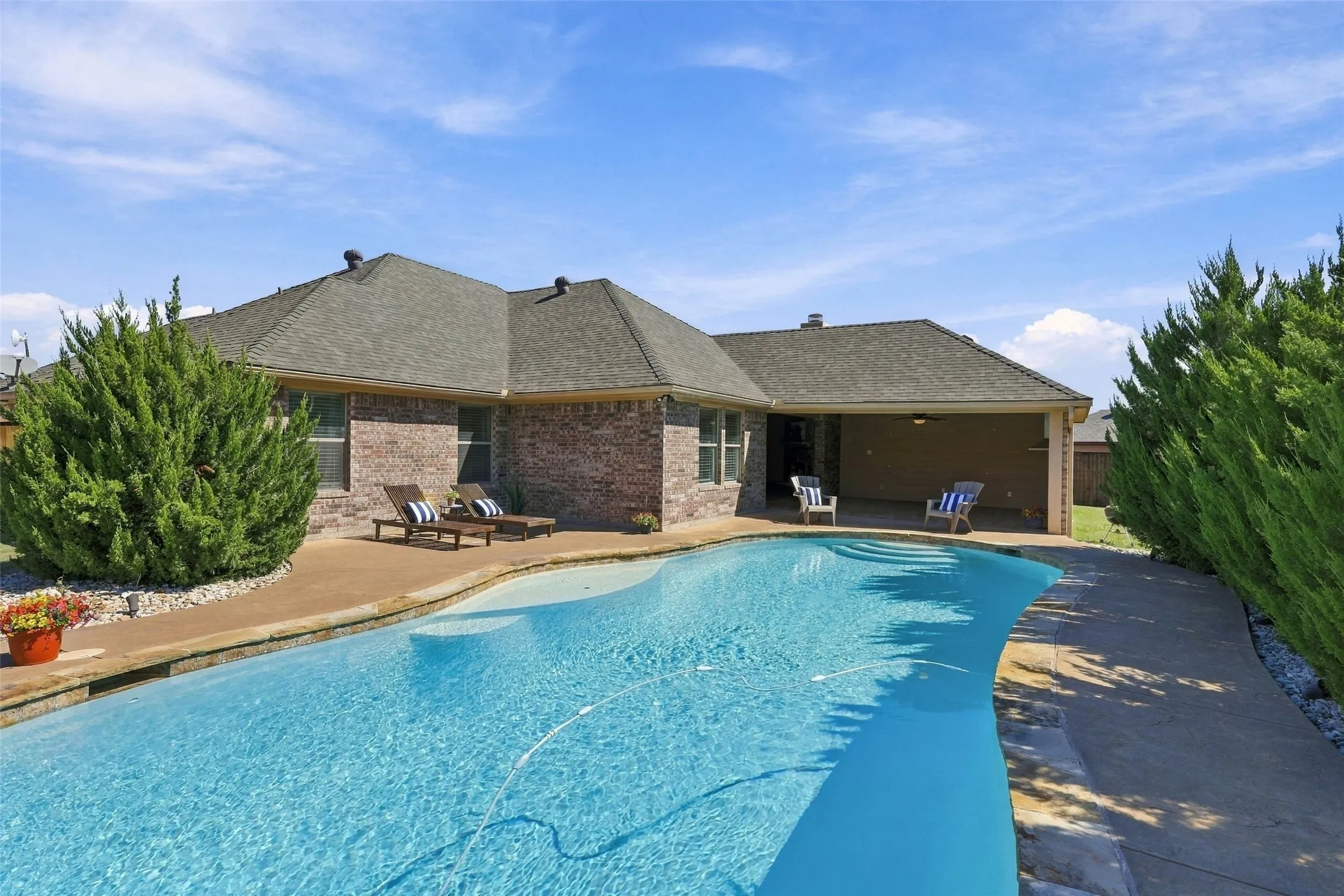 Rear Exterior: Inviting backyard retreat showcases a swimming pool, poolside lounging areas, and a spacious covered patio.