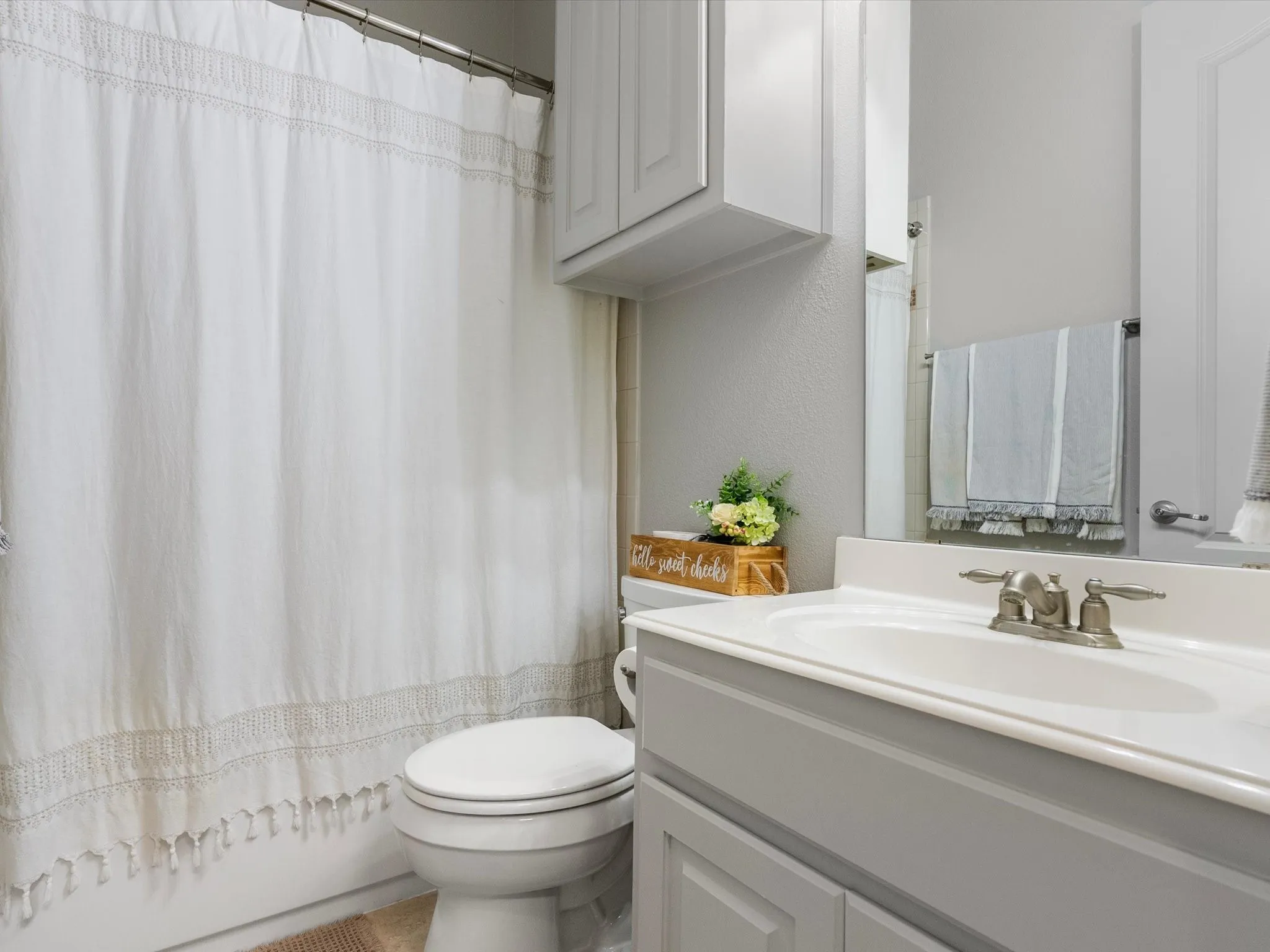 First-level full bathroom with shower/tub combo and storage cabinets