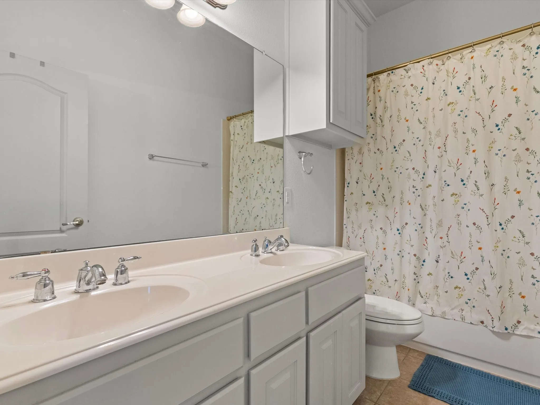 Upstairs full bathroom with dual sinks, shower/tub combo, and built-in storage