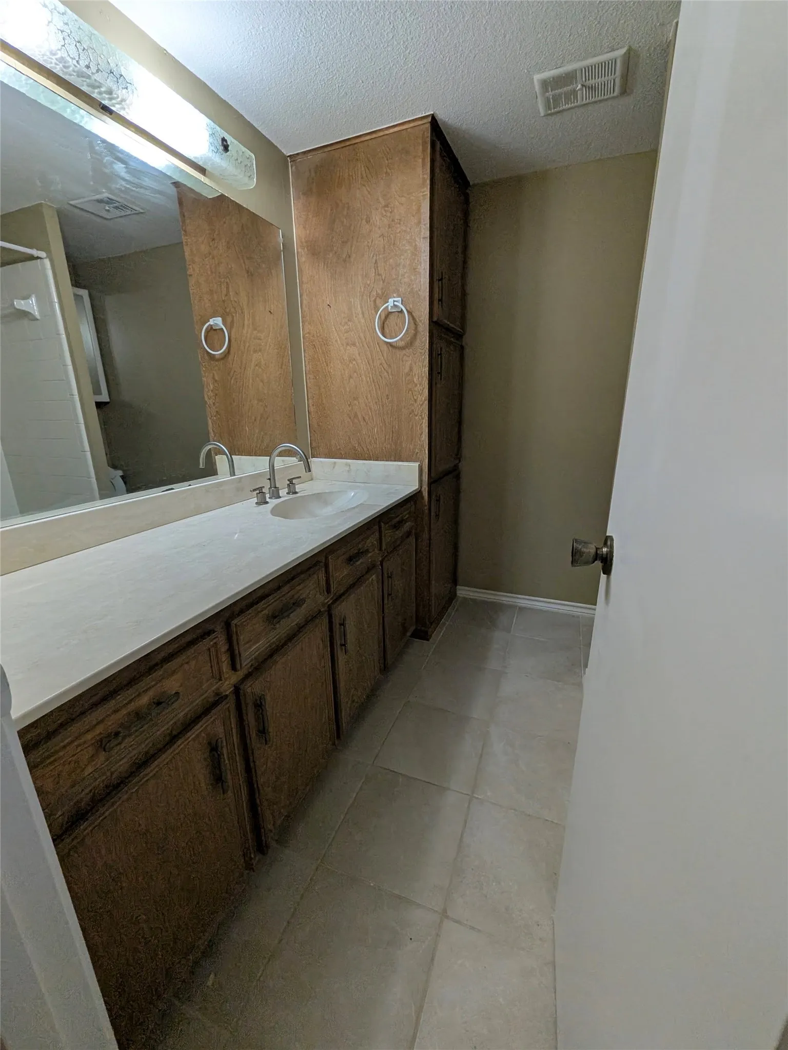 Vanity with integrated sink, wood-finish cabinetry, and a full-width mirror
