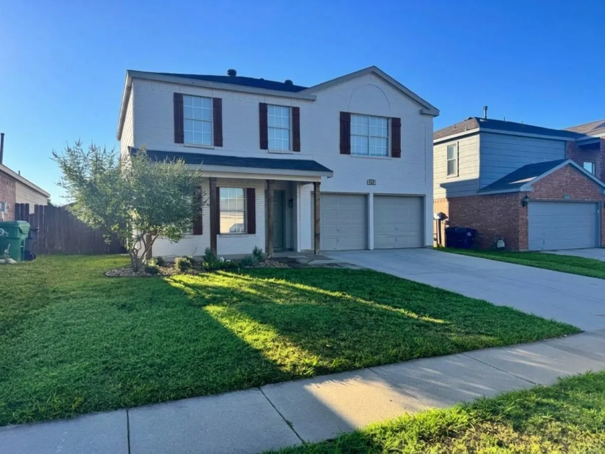 Two-story exterior with a covered entry, dual garage doors, and decorative window shutters