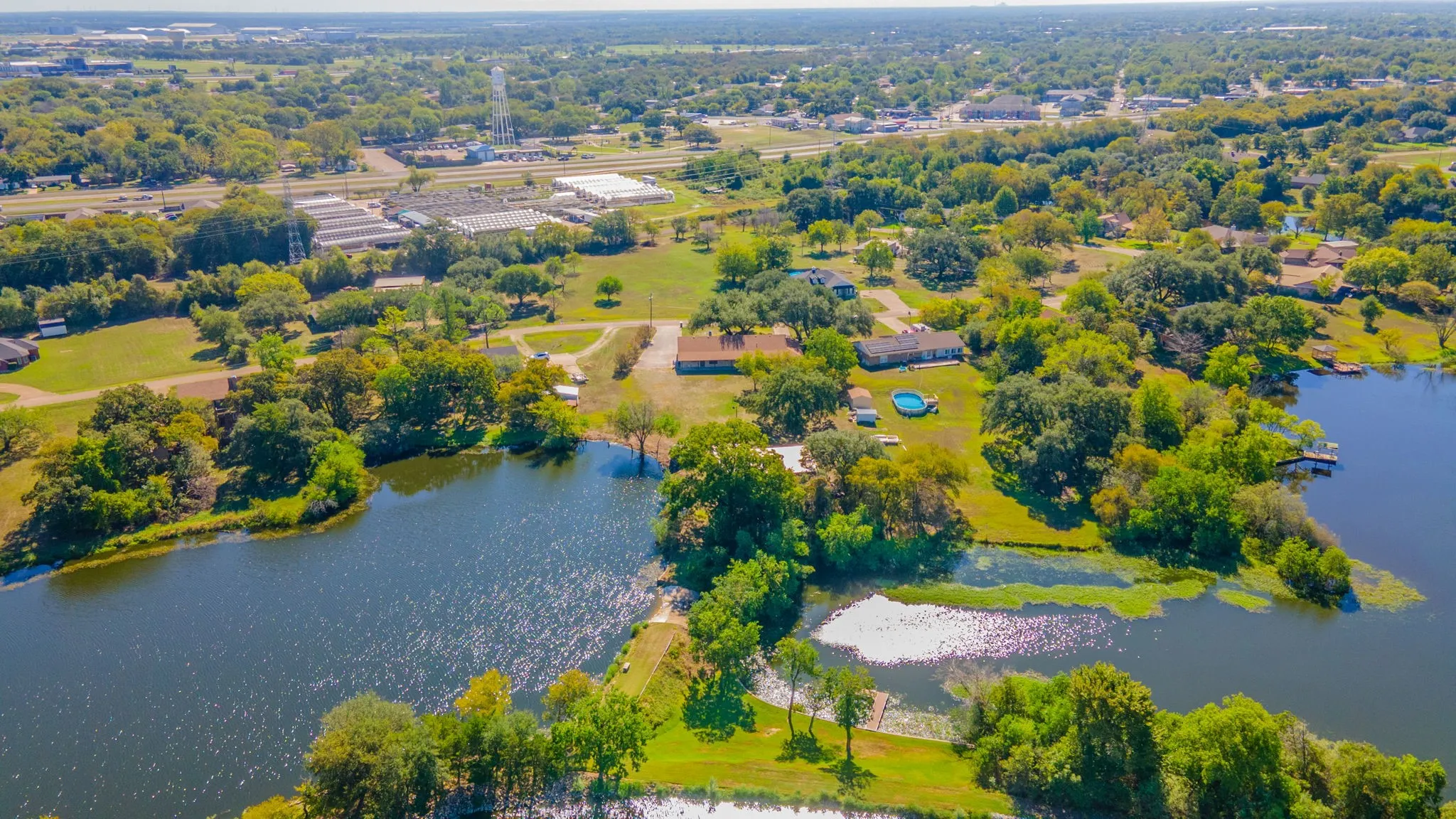 Expansive property featuring a tranquil lake, multiple residential structures, and mature trees