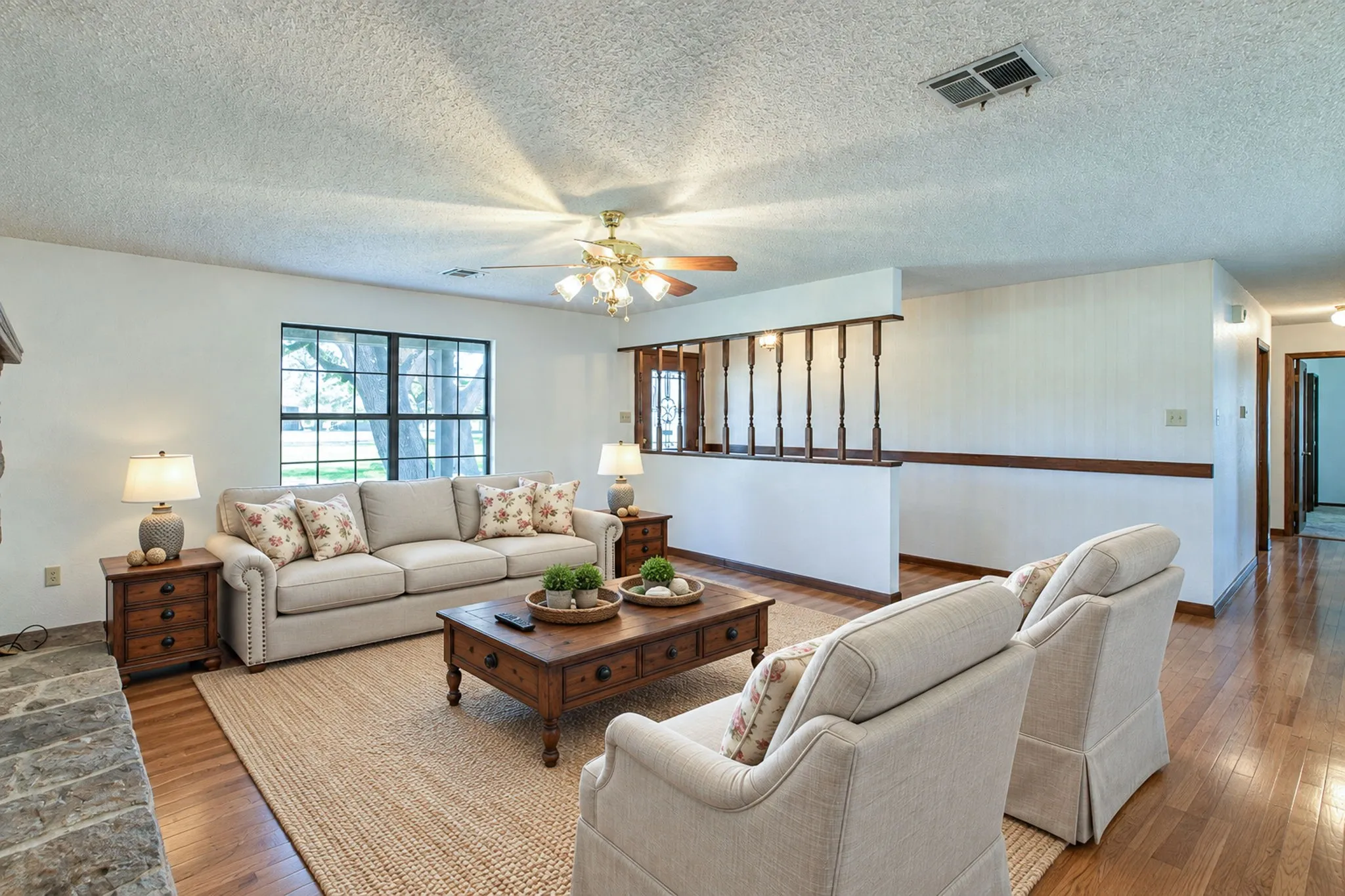Wood-finish flooring in living area and hall, complemented by a stone hearth