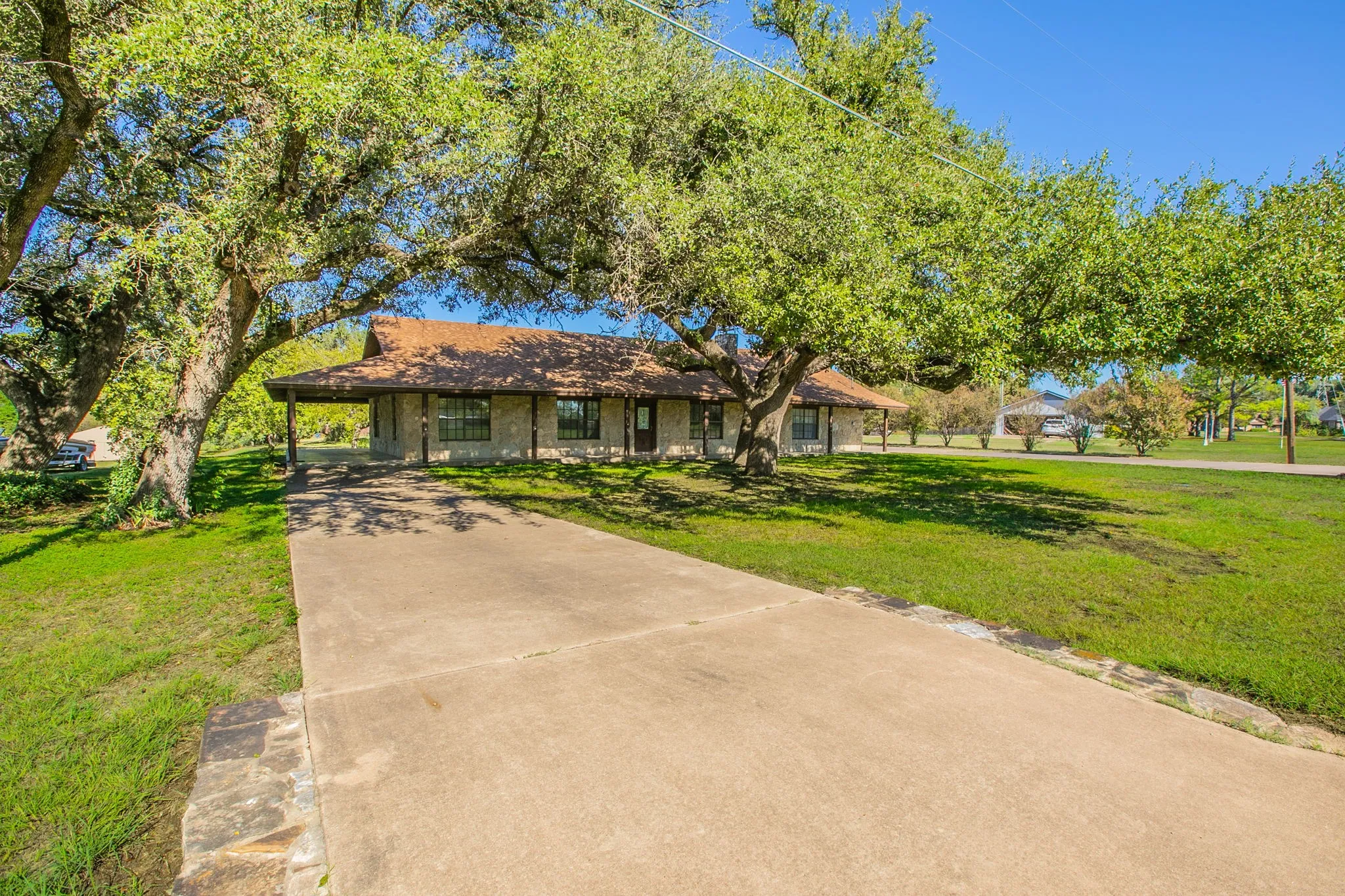 Stone exterior with a covered porch,, a concrete driveway on this side leads to a covered carport which connects to the covered wrap around porch!  That's right.  There are 2 driveways!