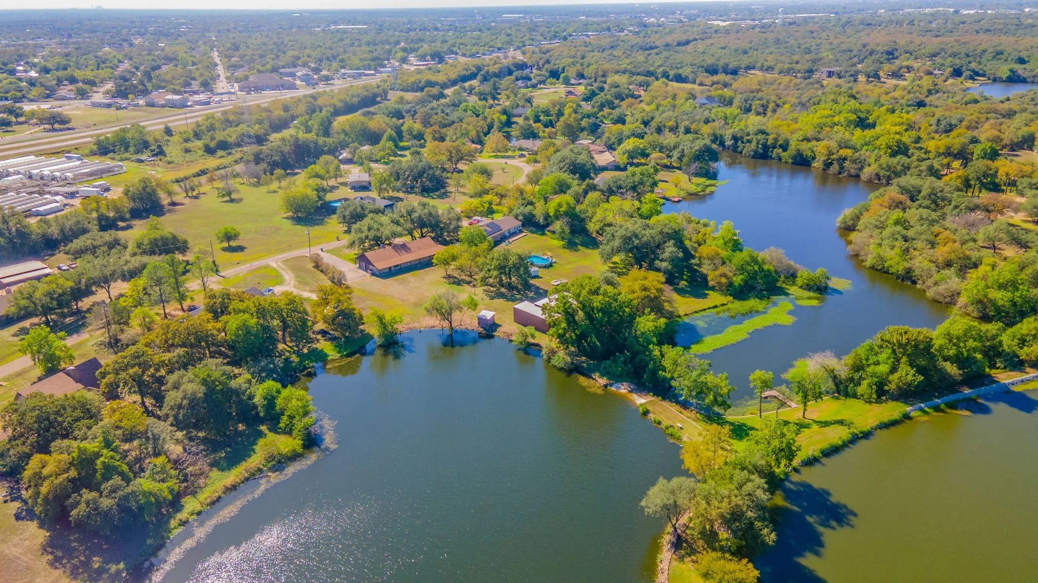 Expansive property featuring multiple bodies of water, extensive tree coverage, and visible structures