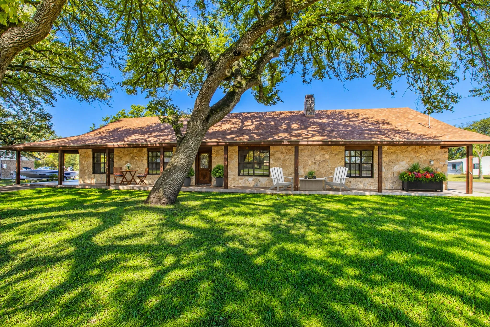 Stone exterior with a covered front porch and  prominent mature trees.  Driveway to the covered carport on the left and driveway to the 2 car side garage on the right side! All pictures are virtually staged and the grass is greener in pics!!