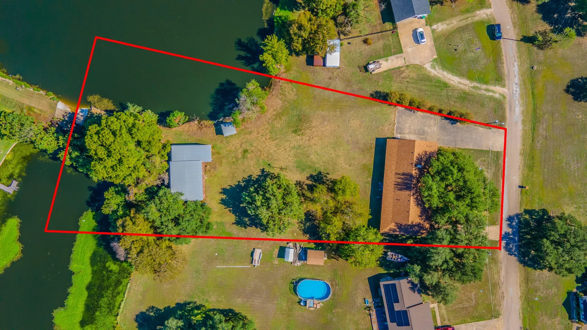Waterfront property featuring direct water access on both sides, a main residence with a brown shingle roof, and a 2 level workshop/RV storage area with a metal​​‌​​​​‌​​‌‌​‌‌​​​‌‌​‌​‌​‌​​​‌​​ roof