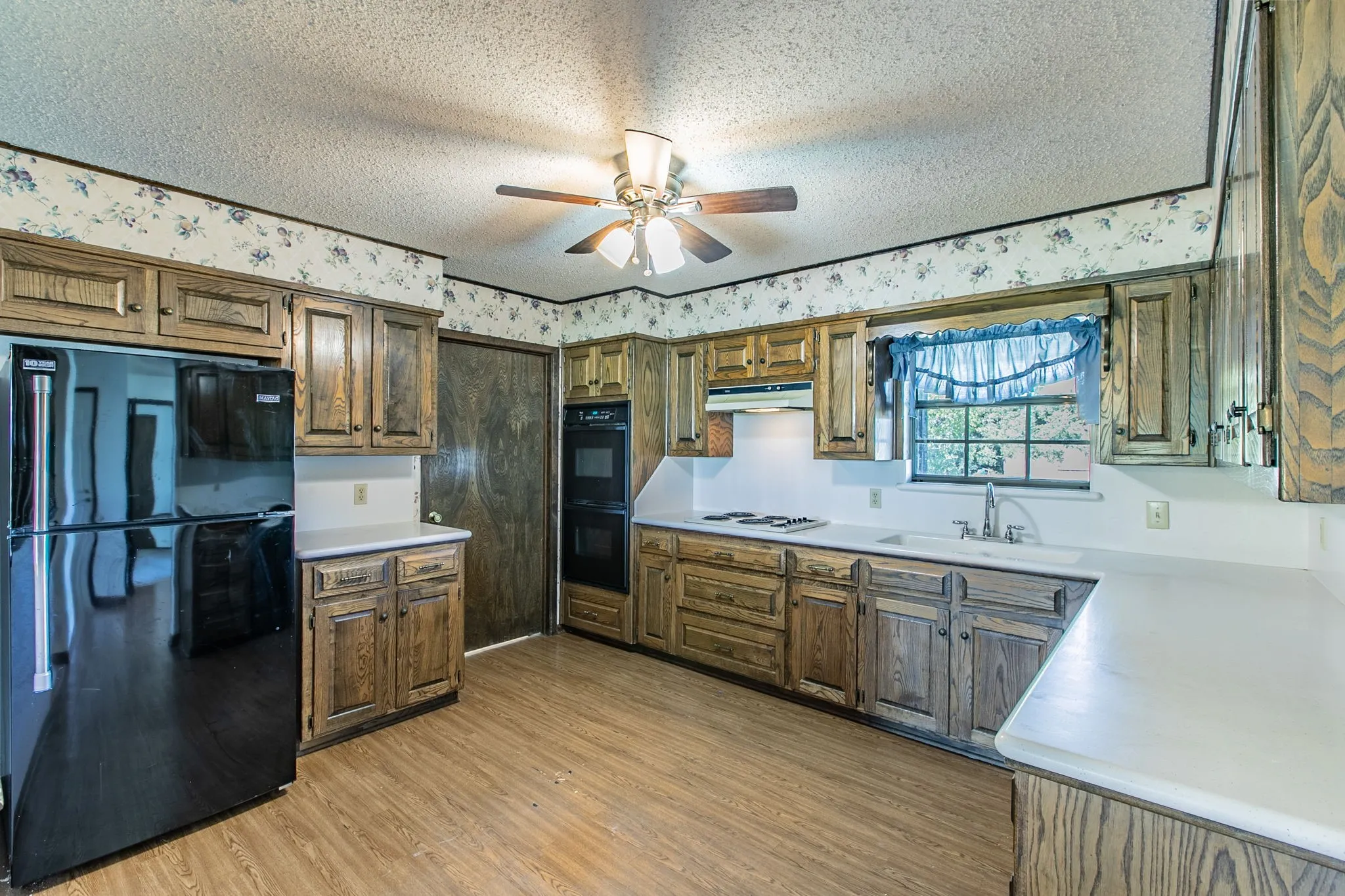 Kitchen featuring wood-finish cabinetry, white countertops, a built-in double oven, and a ceiling fan.  Refrigerator does not convey with the property.