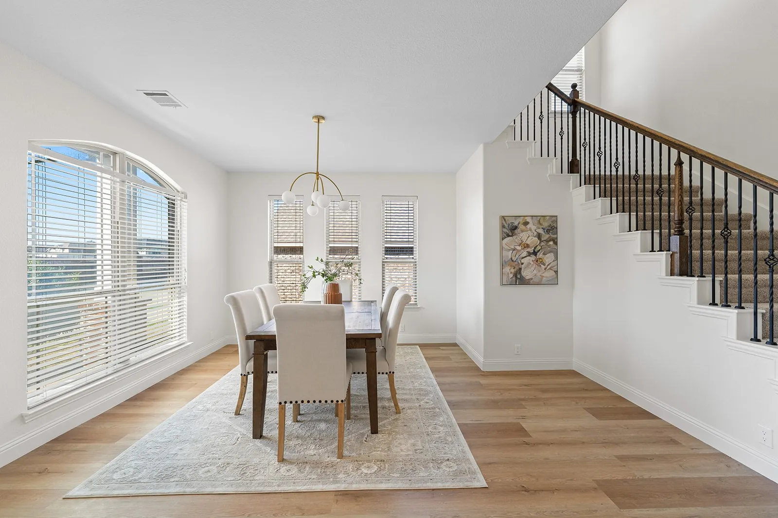Arch-top window, wood-finish flooring, wrought iron staircase with wood handrail, modern chandelier, recessed lighting