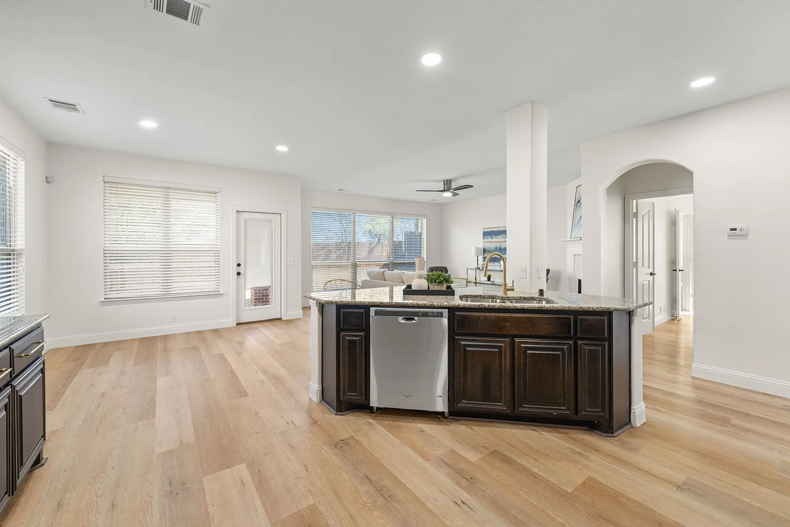 Open concept living space featuring wood-finish flooring, recessed lighting, and an arched doorway