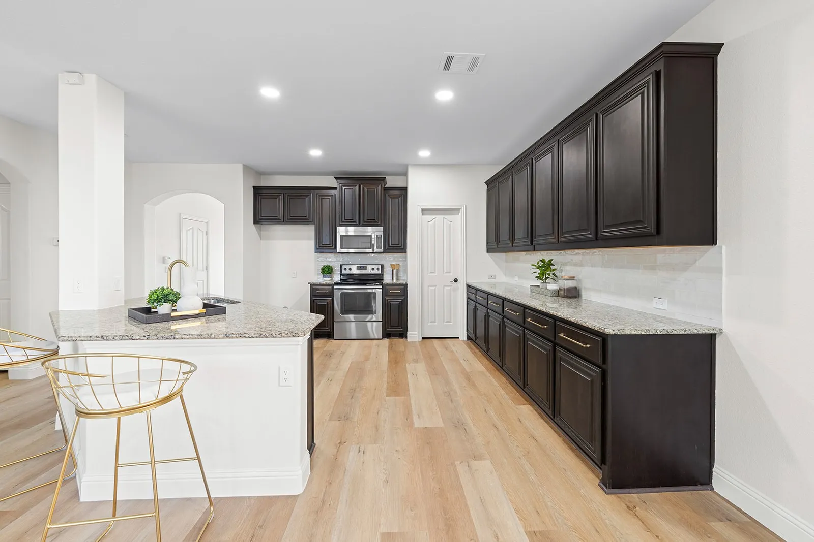 Wood-finish flooring throughout, dark wood-finish cabinetry, granite countertops, stainless steel appliances, and a tile backsplash