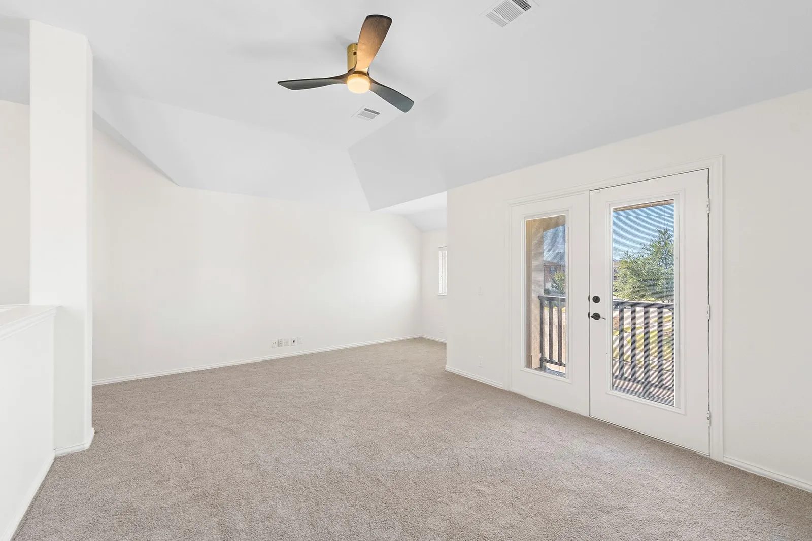 Carpeted room with a ceiling fan, white walls, and French doors leading to a balcony