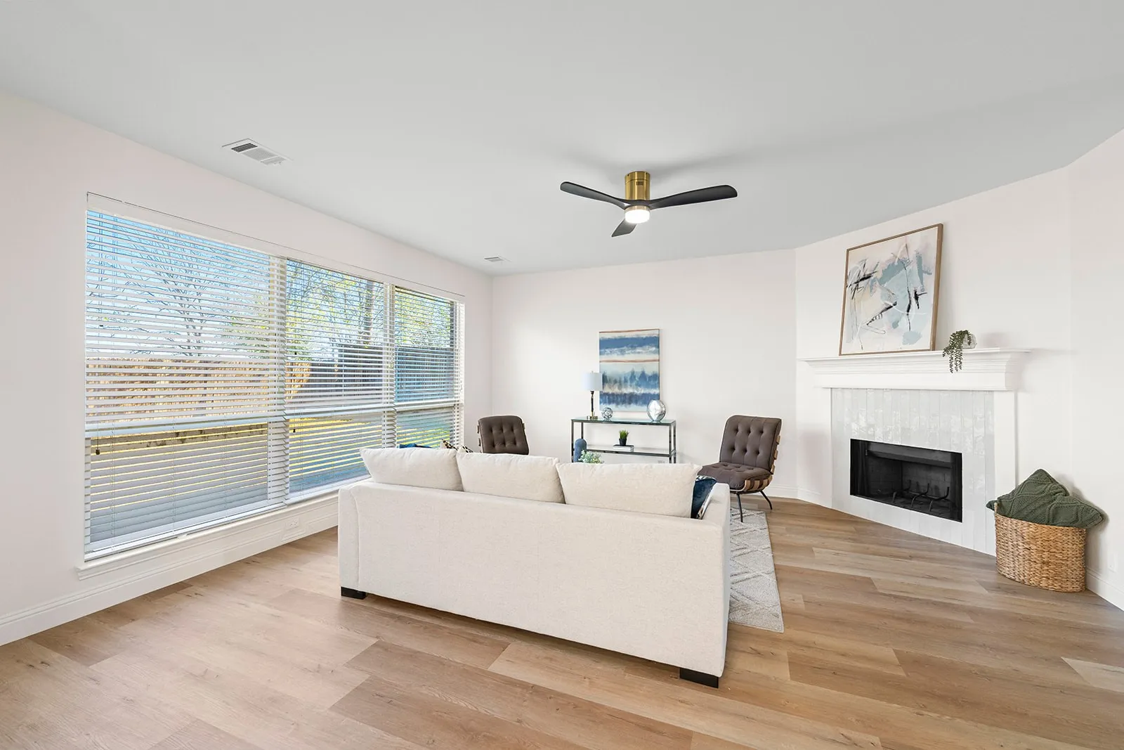 Expansive windows, wood-finish flooring, corner fireplace with white mantel, ceiling fan with light fixture, and recessed lighting