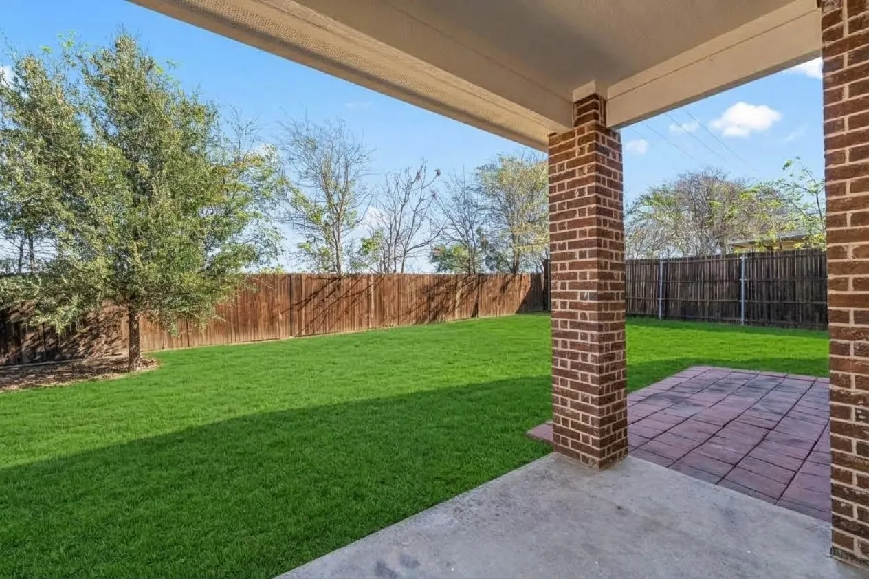 Covered patio with brick columns, concrete flooring, and an additional paver section