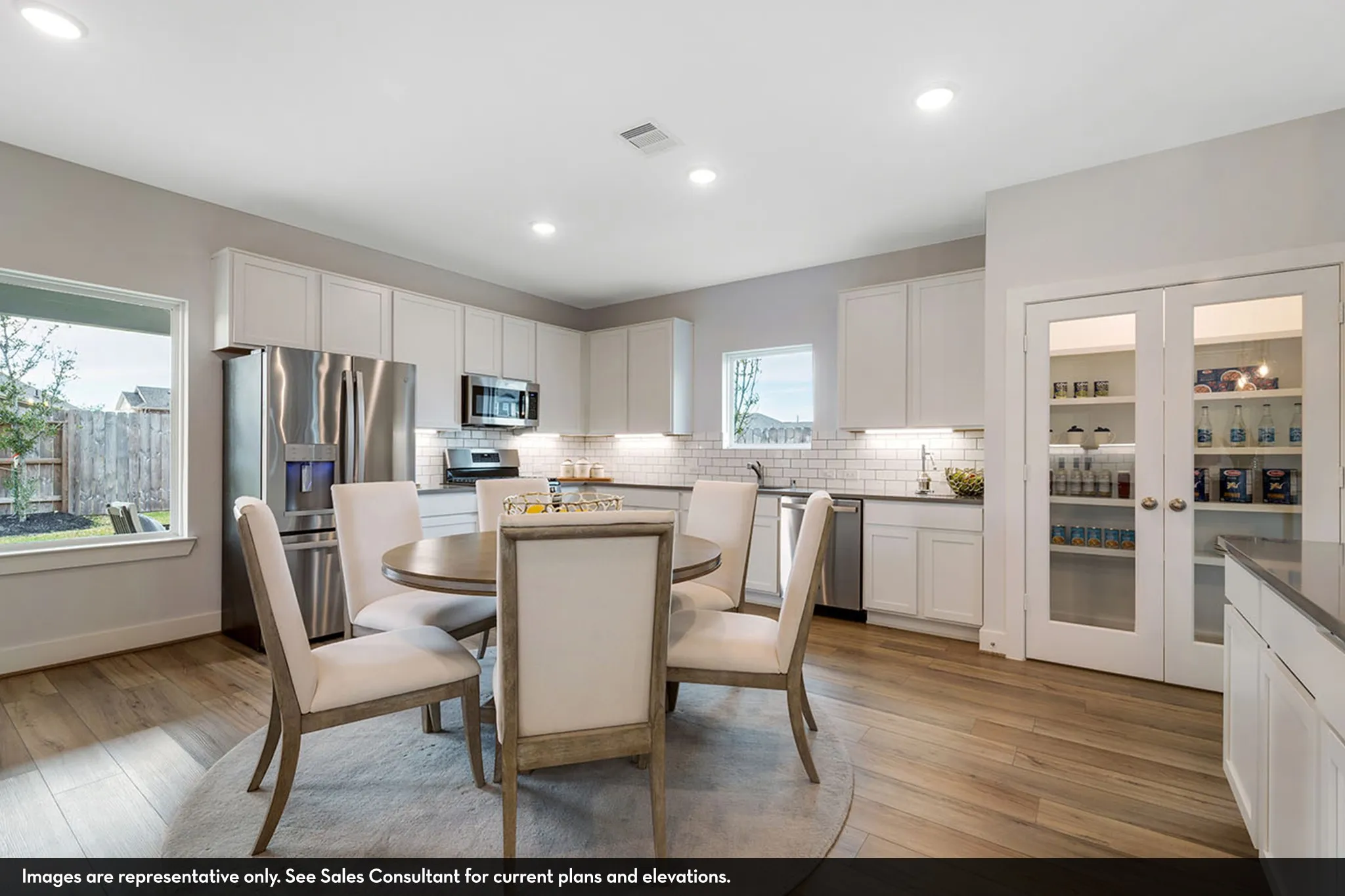 Kitchen featuring white cabinetry, stainless steel appliances, subway tile backsplash, wood-finish flooring, and a built-in pantry with glass-paneled doors