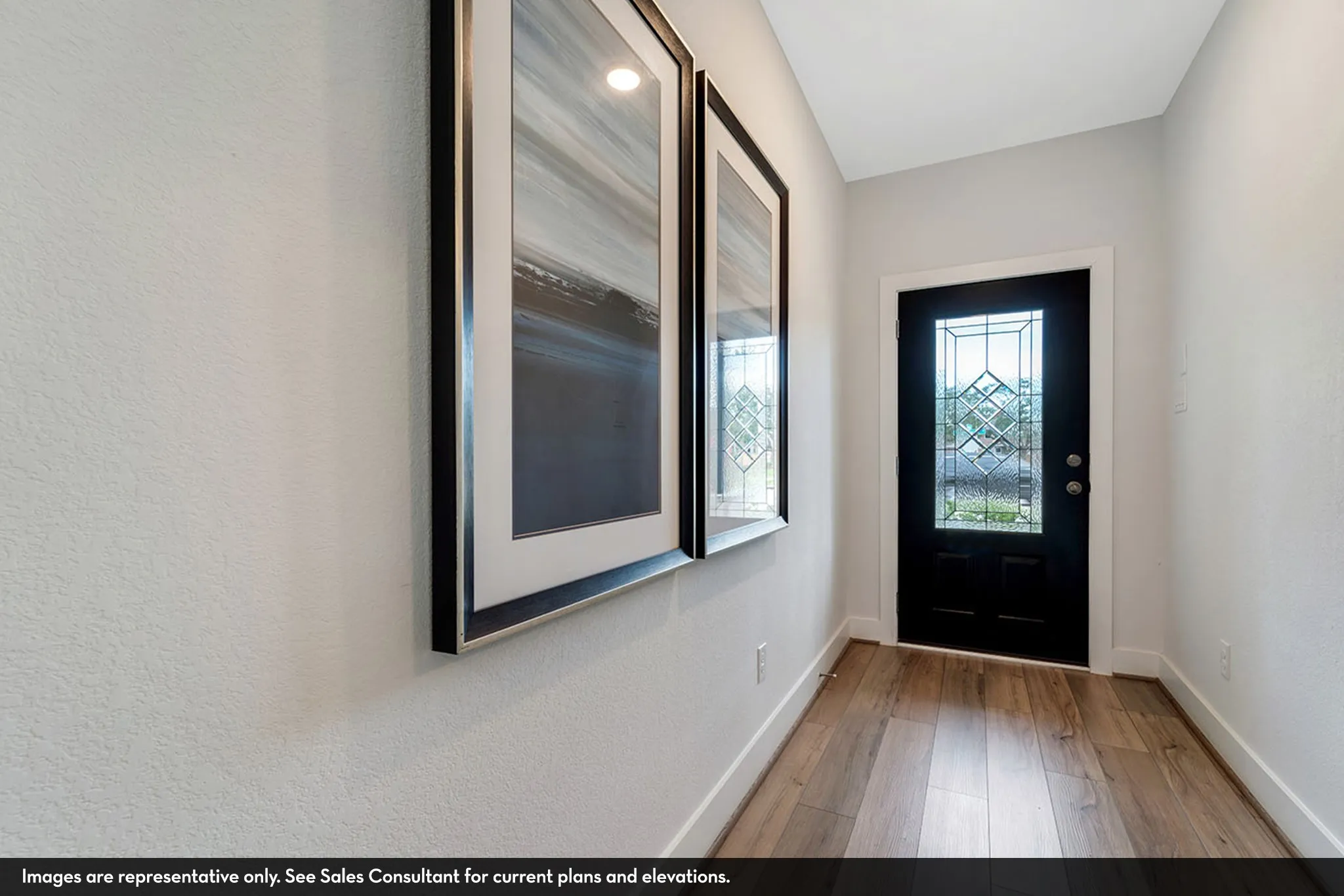 Entryway featuring wood-finish flooring, white baseboards, a black door with leaded glass, and white walls