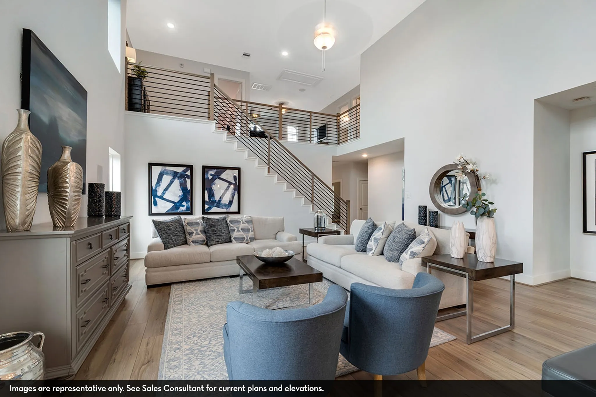 Two-story living area with high ceilings, wood-finish flooring, and a modern staircase with horizontal metal balusters
