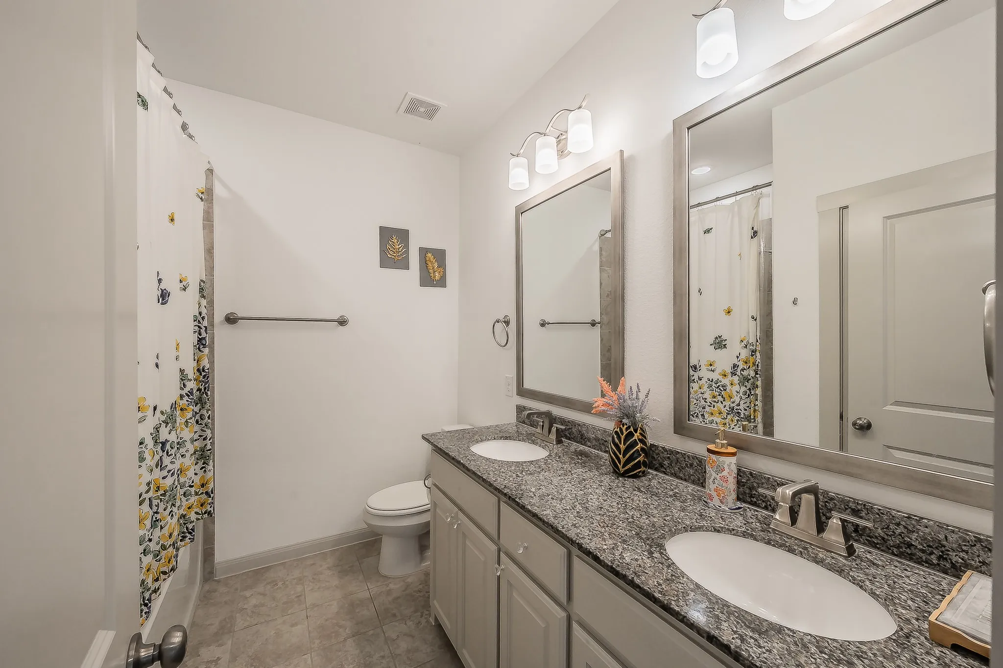 Dual sink vanity with granite countertop, undermount sinks, and framed mirrors, with plenty of storage