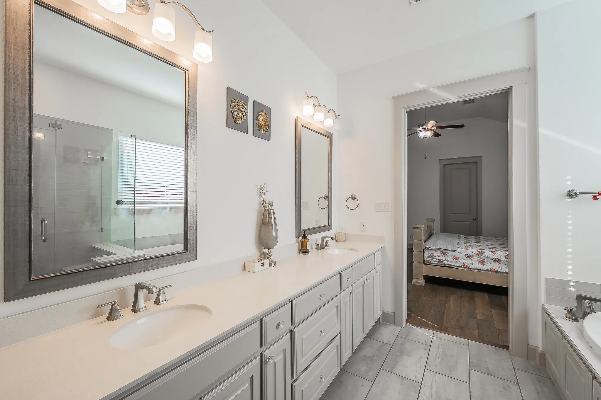 Dual vanity with gray cabinetry, white countertops, brushed nickel fixtures, and framed mirrors