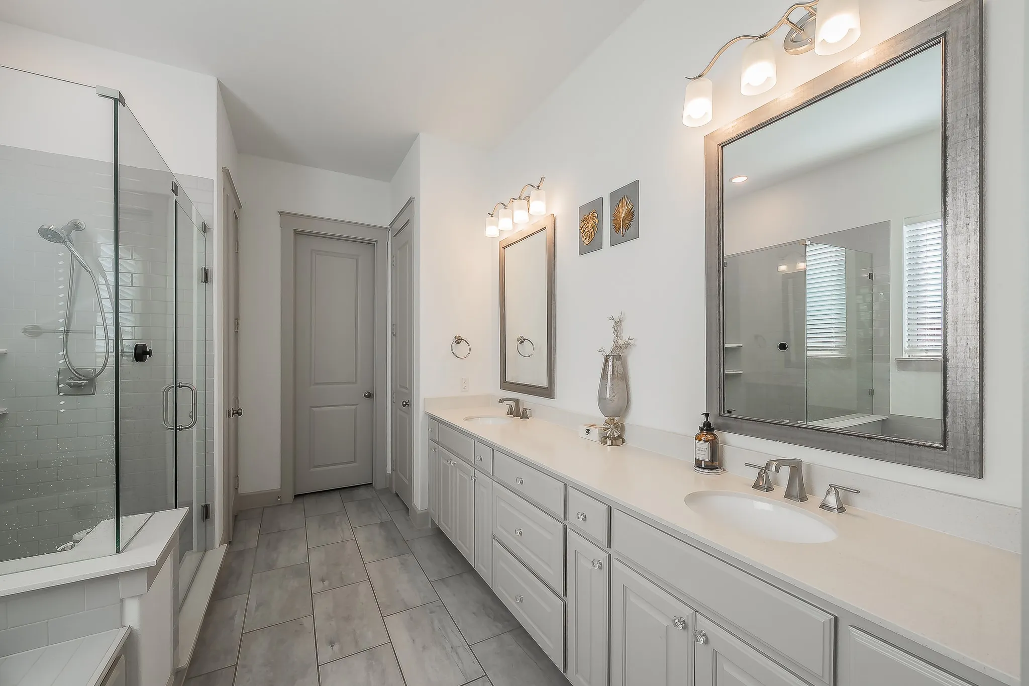 Dual sink vanity with plenty of storage, quartz countertops, and framed mirrors