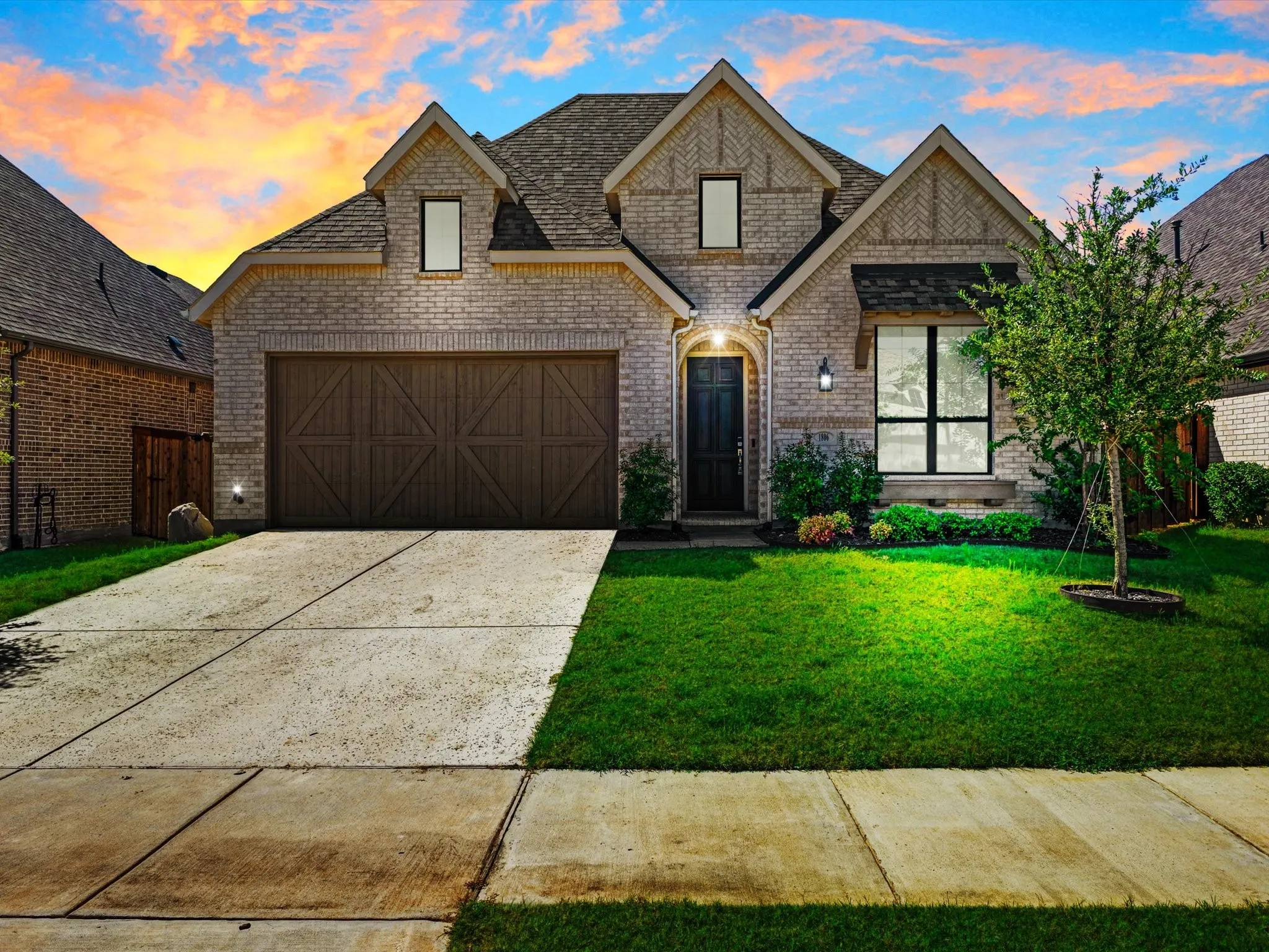 Brick facade with gabled roof lines, featuring a wood-panel garage door and a covered entry