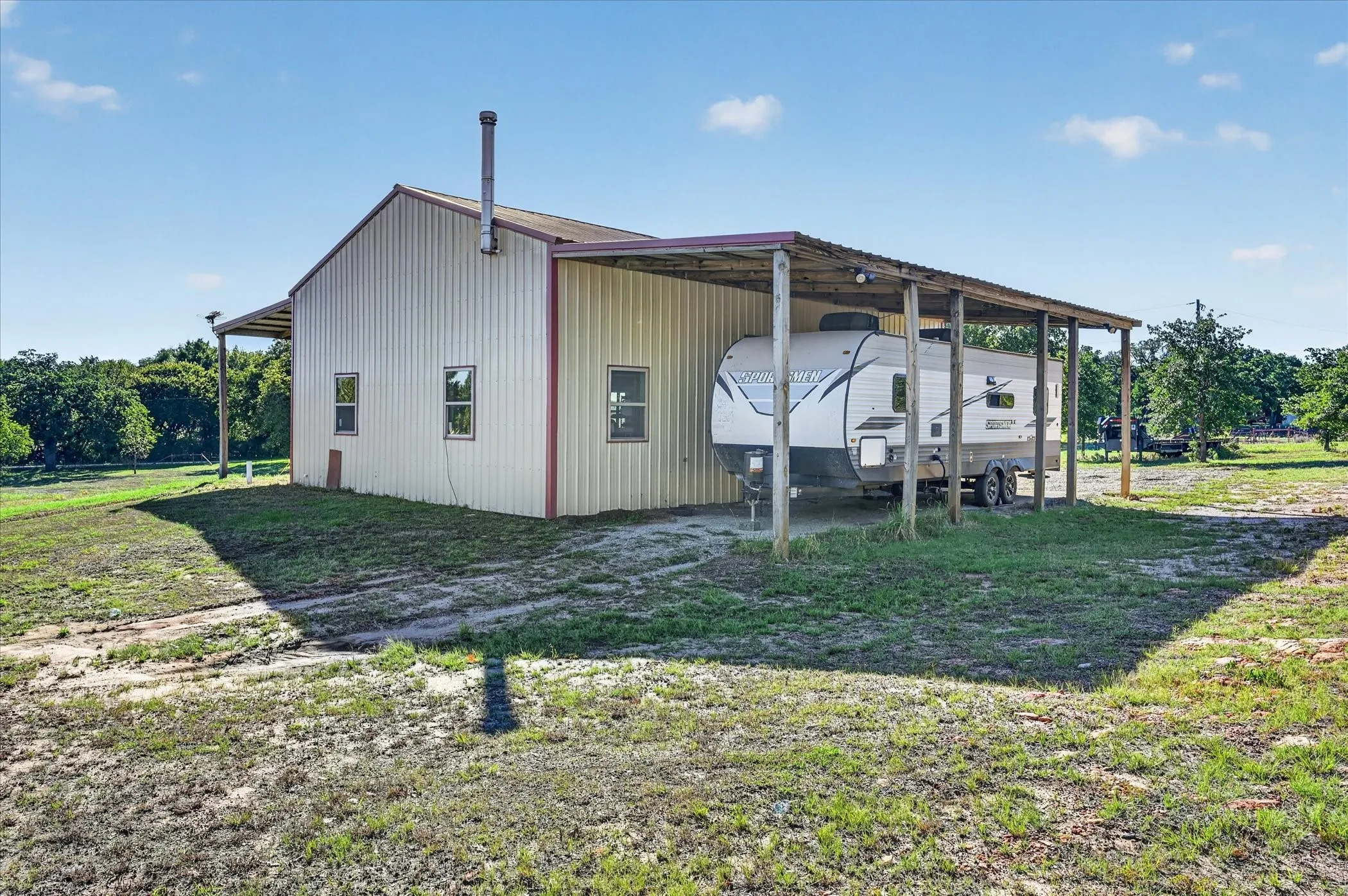 Metal-sided building with multiple windows and a covered side storage area