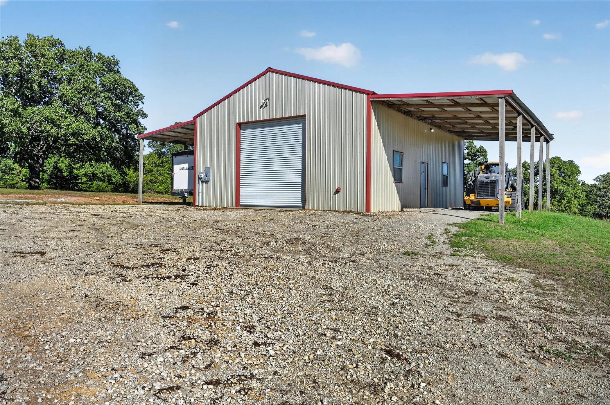 Metal building with a rolled garage door, an attached carport, and a second covered extension