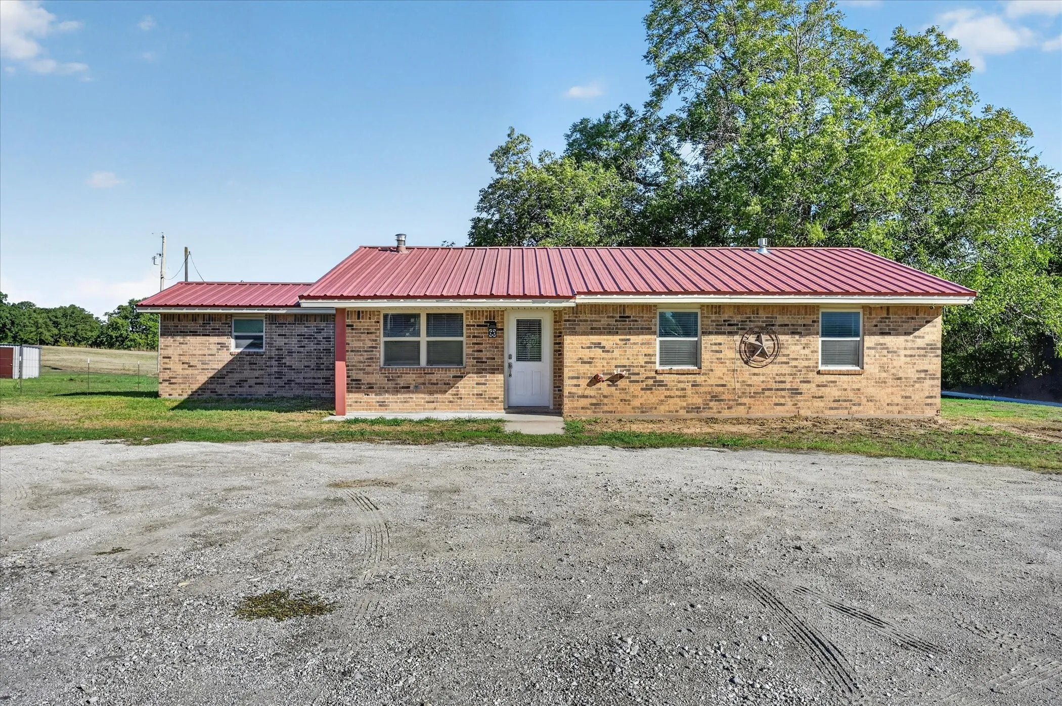 Brick exterior with a red metal roof and a gravel front area