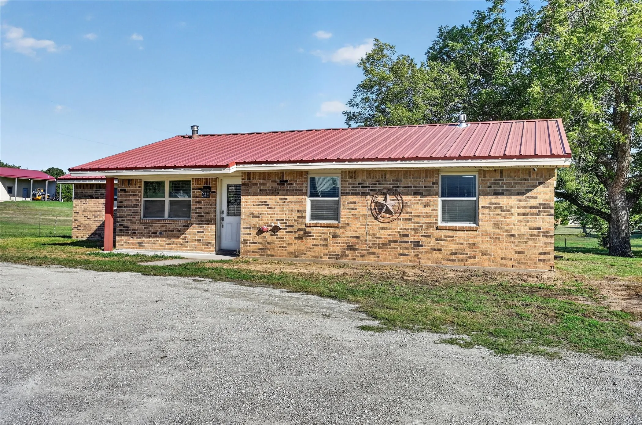 Brick exterior with a red metal roof, covered entry, and multiple windows