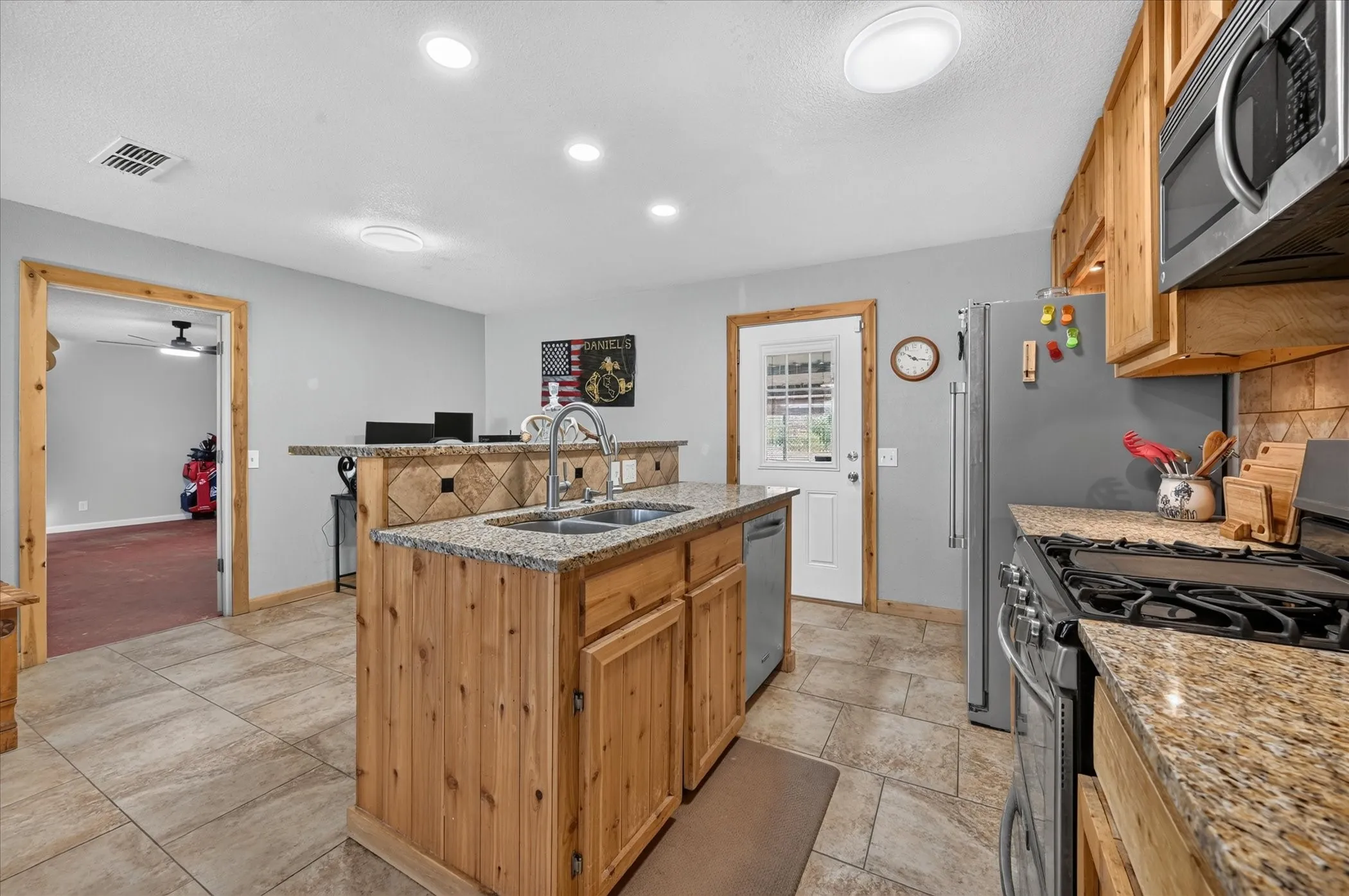 Kitchen featuring natural wood cabinetry, granite countertops, stainless steel appliances, tile flooring, and recessed lighting