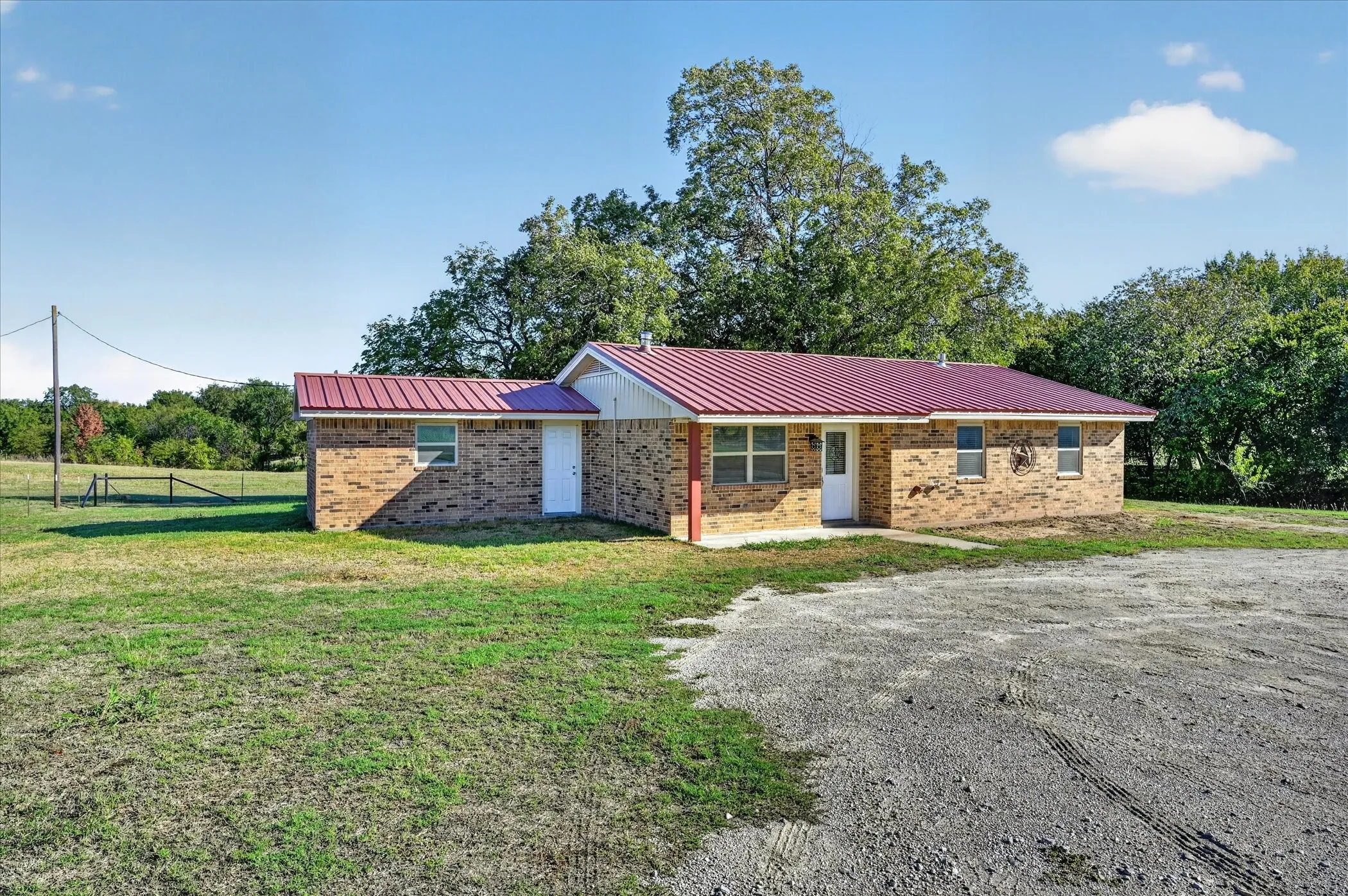 Brick exterior with a red metal roof, covered front entry, and multiple windows