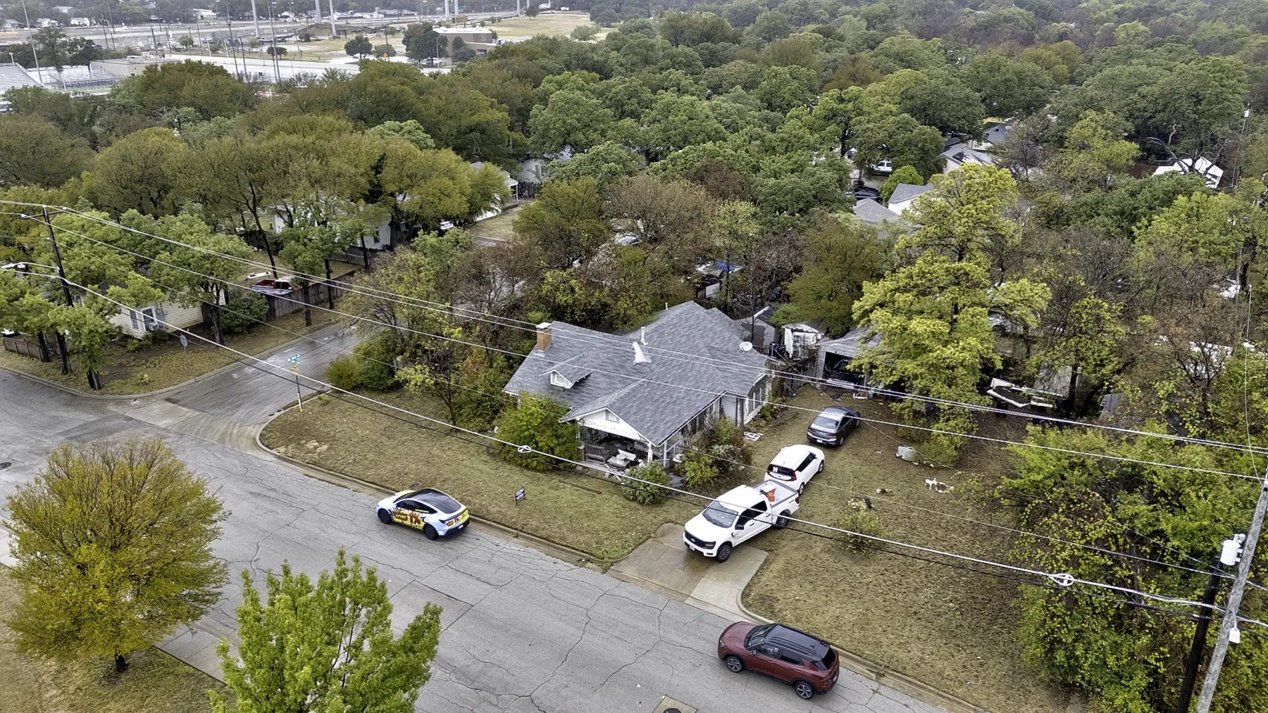 Elevated corner view of the home, front and side yards, driveway and the trees that line the 9,750 sq ft lot