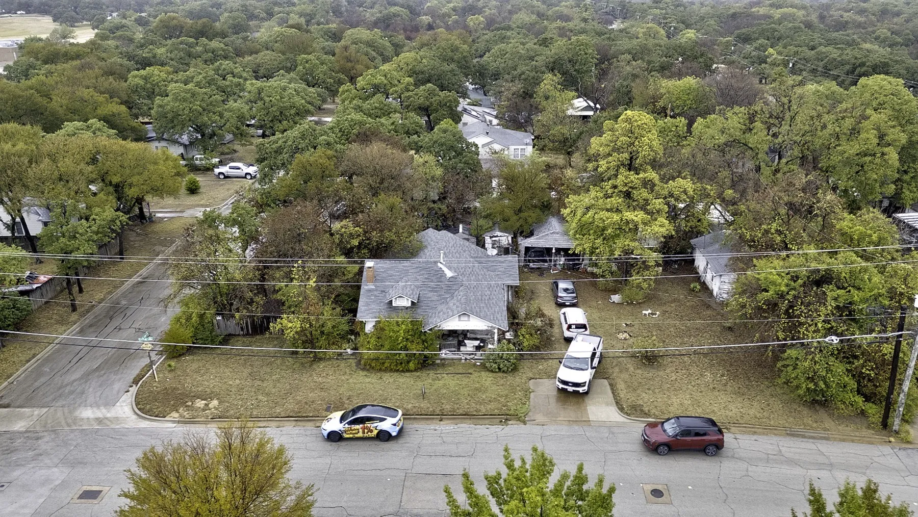 Front view of the home on its wide corner lot with a covered porch, chimney, concrete drive and mature trees