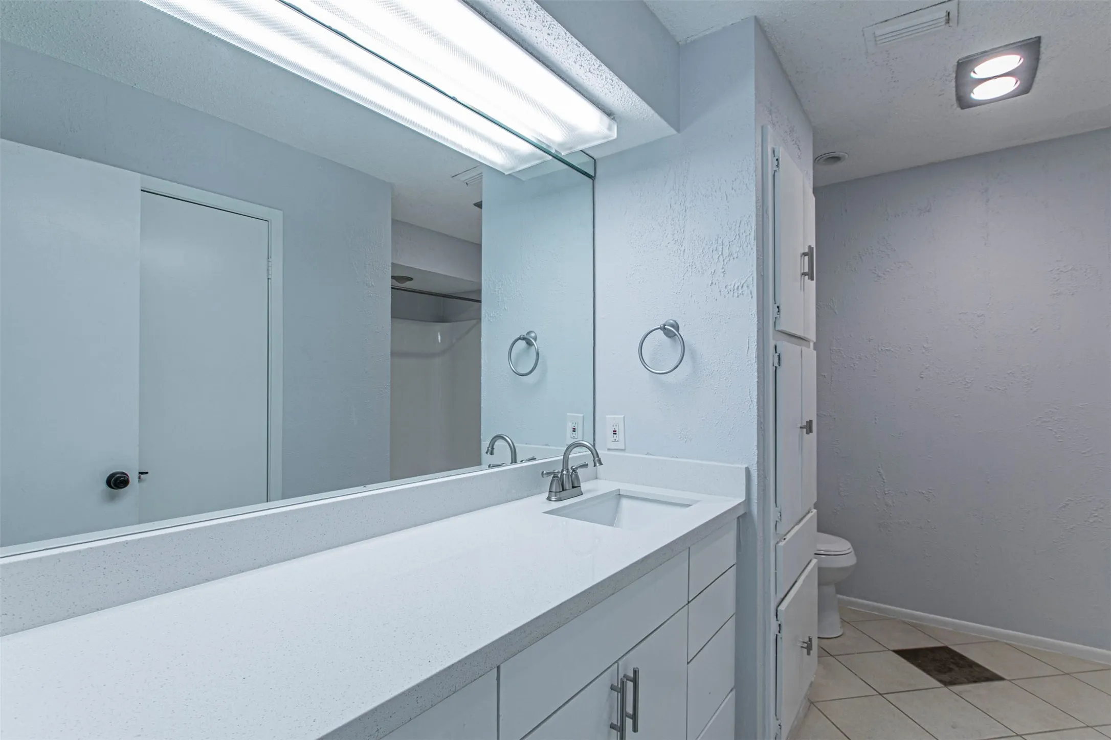 Bathroom3 featuring light tile patterned floors, vanity, and a textured wall