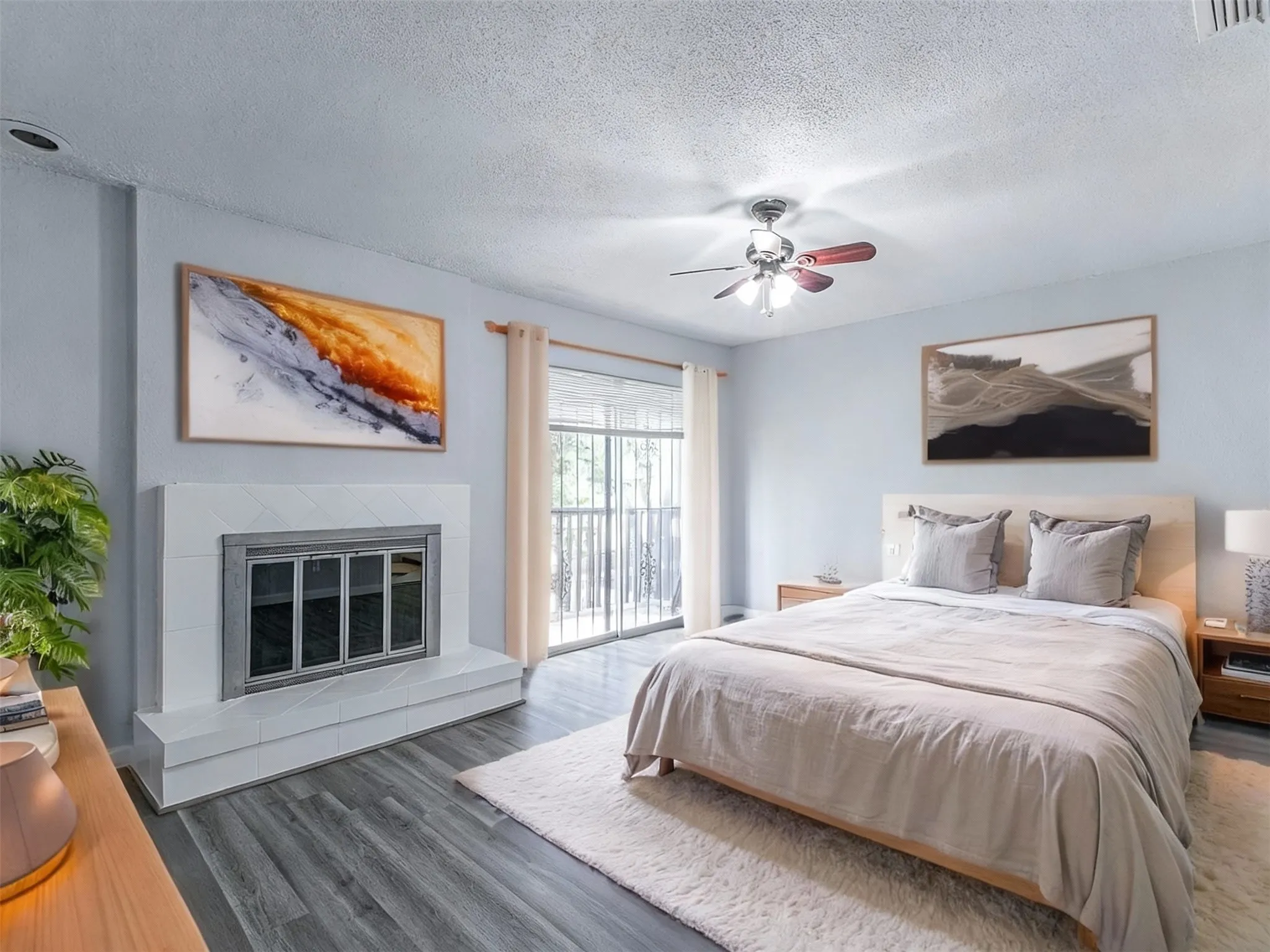 Bedroom featuring a tiled fireplace, access to outside, wood finished floors, a textured ceiling, and a ceiling fan