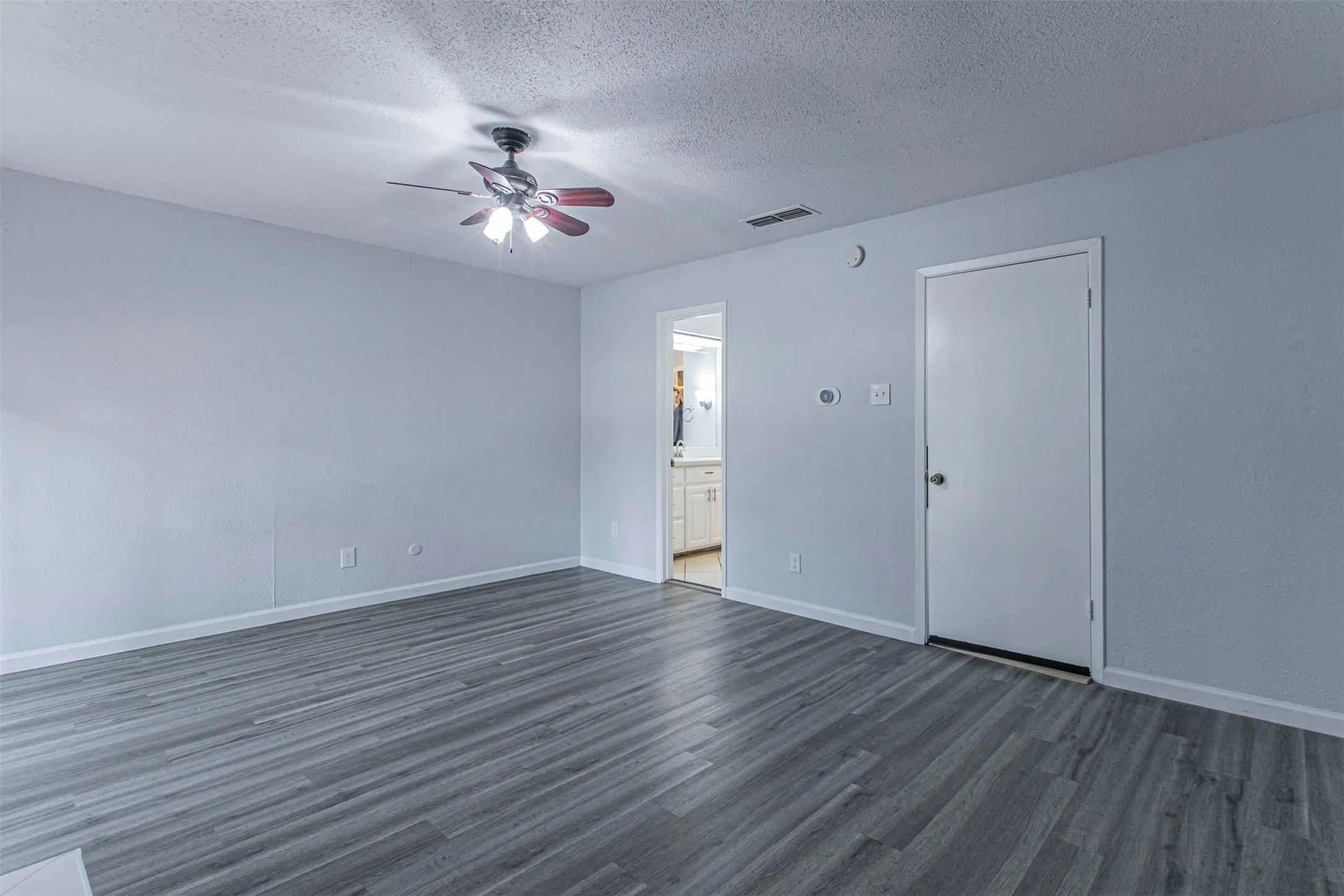bedroom  3with dark wood-style floors, a textured ceiling, a ceiling fan, and ensuite bath