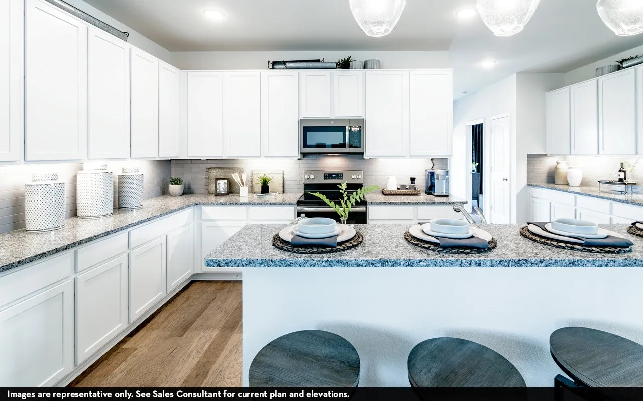 Expansive kitchen featuring white cabinetry, light-toned countertops, tile backsplash, stainless steel appliances, and wood-finish flooring