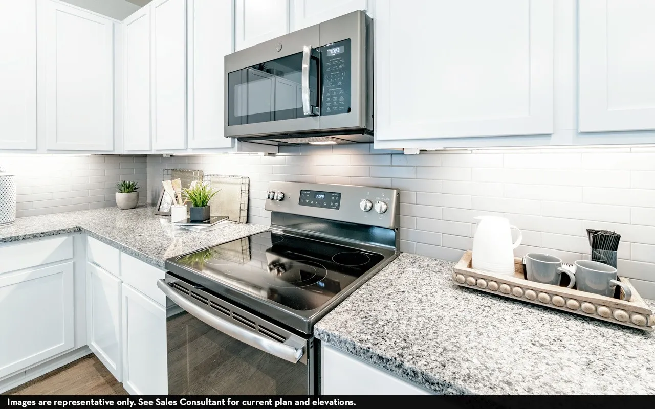 White shaker cabinetry, stainless steel appliances, speckled stone countertops, and white subway tile backsplash