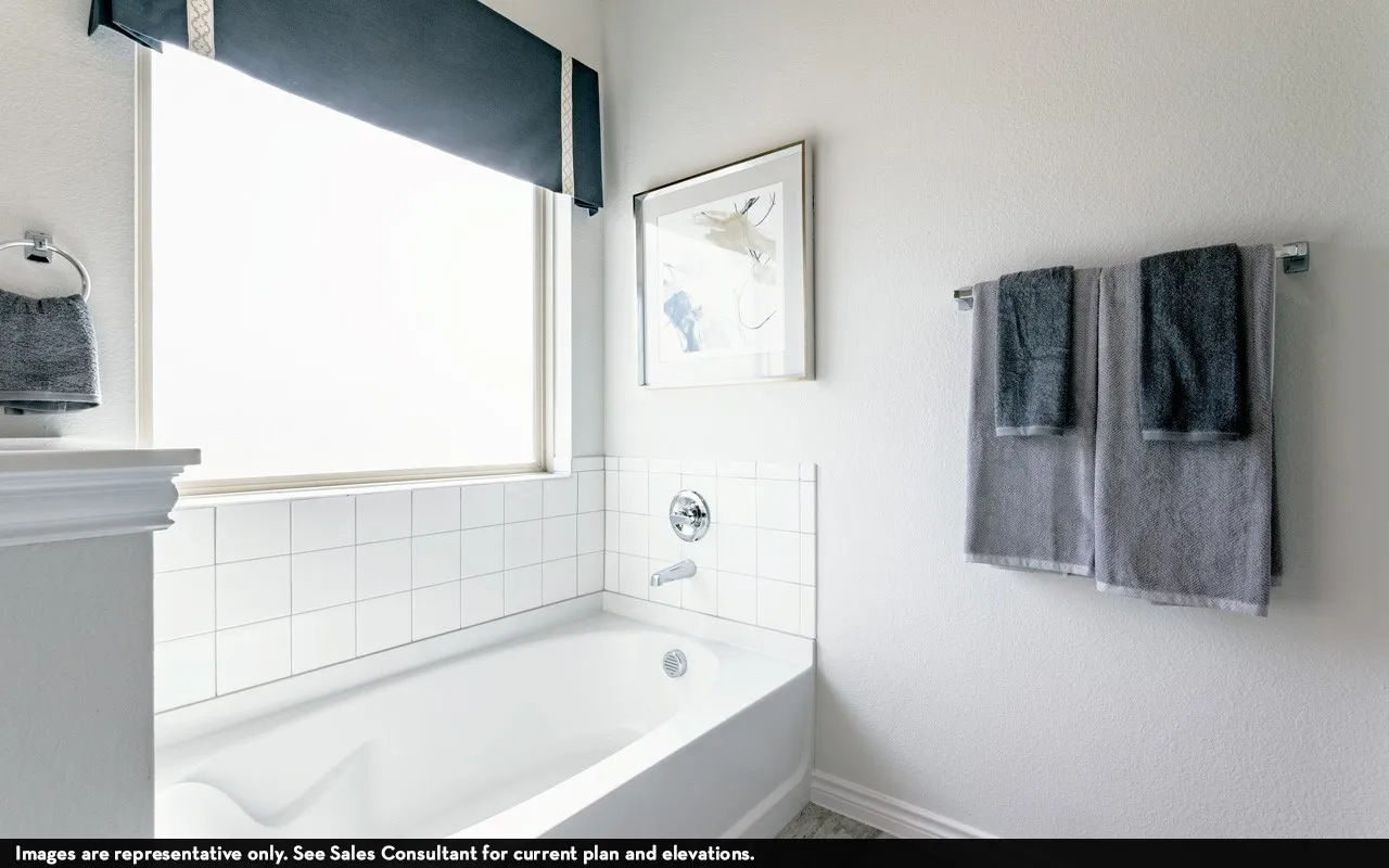 White tile tub surround, chrome fixtures, and a window with a valance