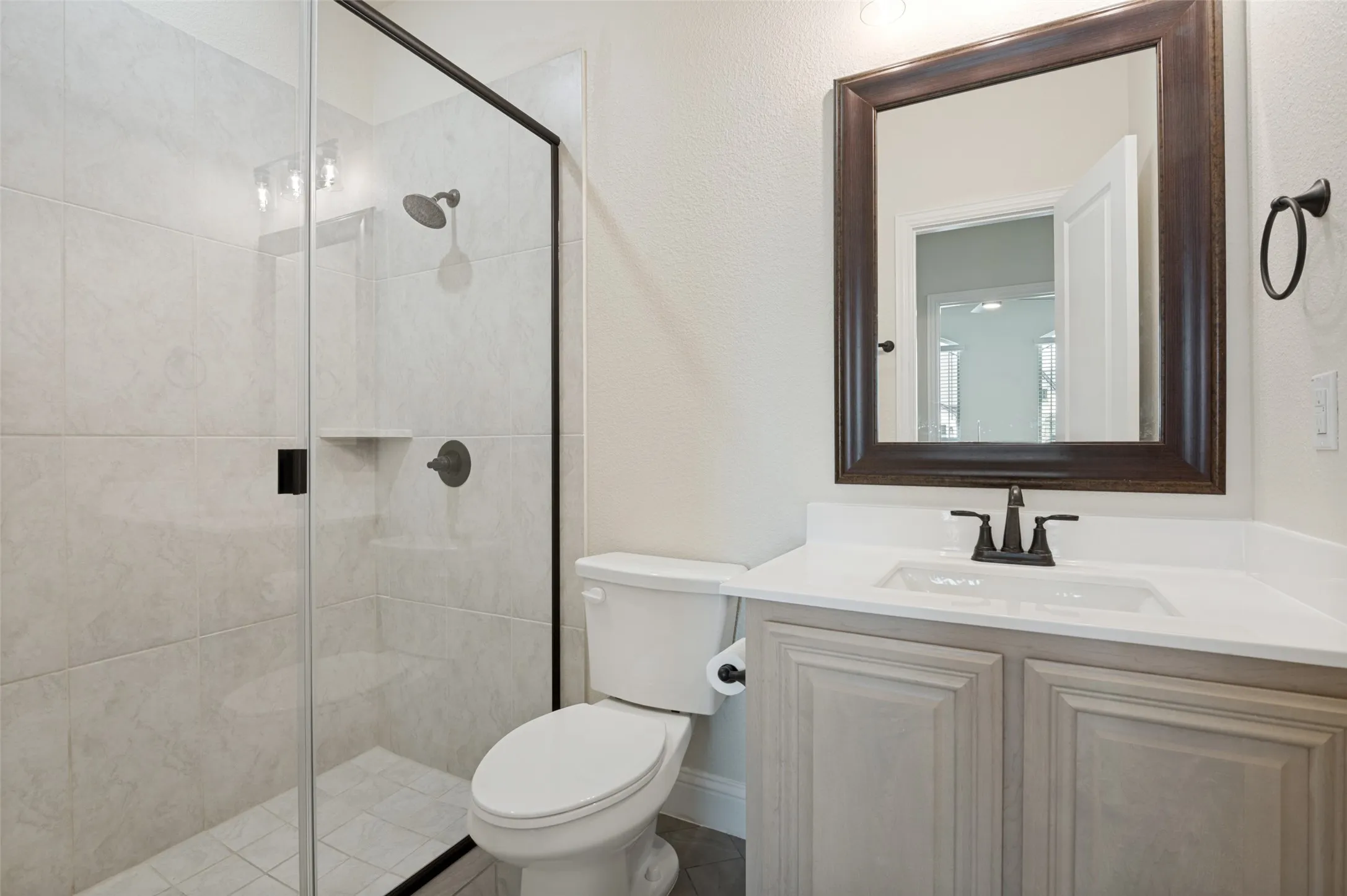 Walk-in shower with clear glass enclosure and tiled surround