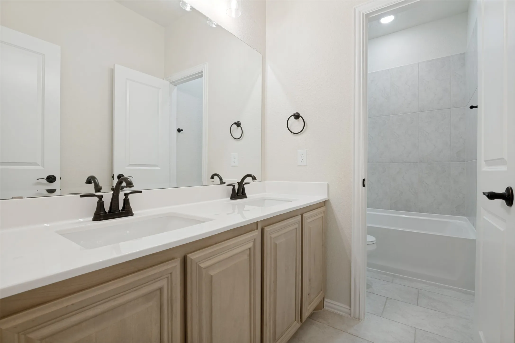 Double vanity with integrated sinks, light-toned cabinetry, and black hardware