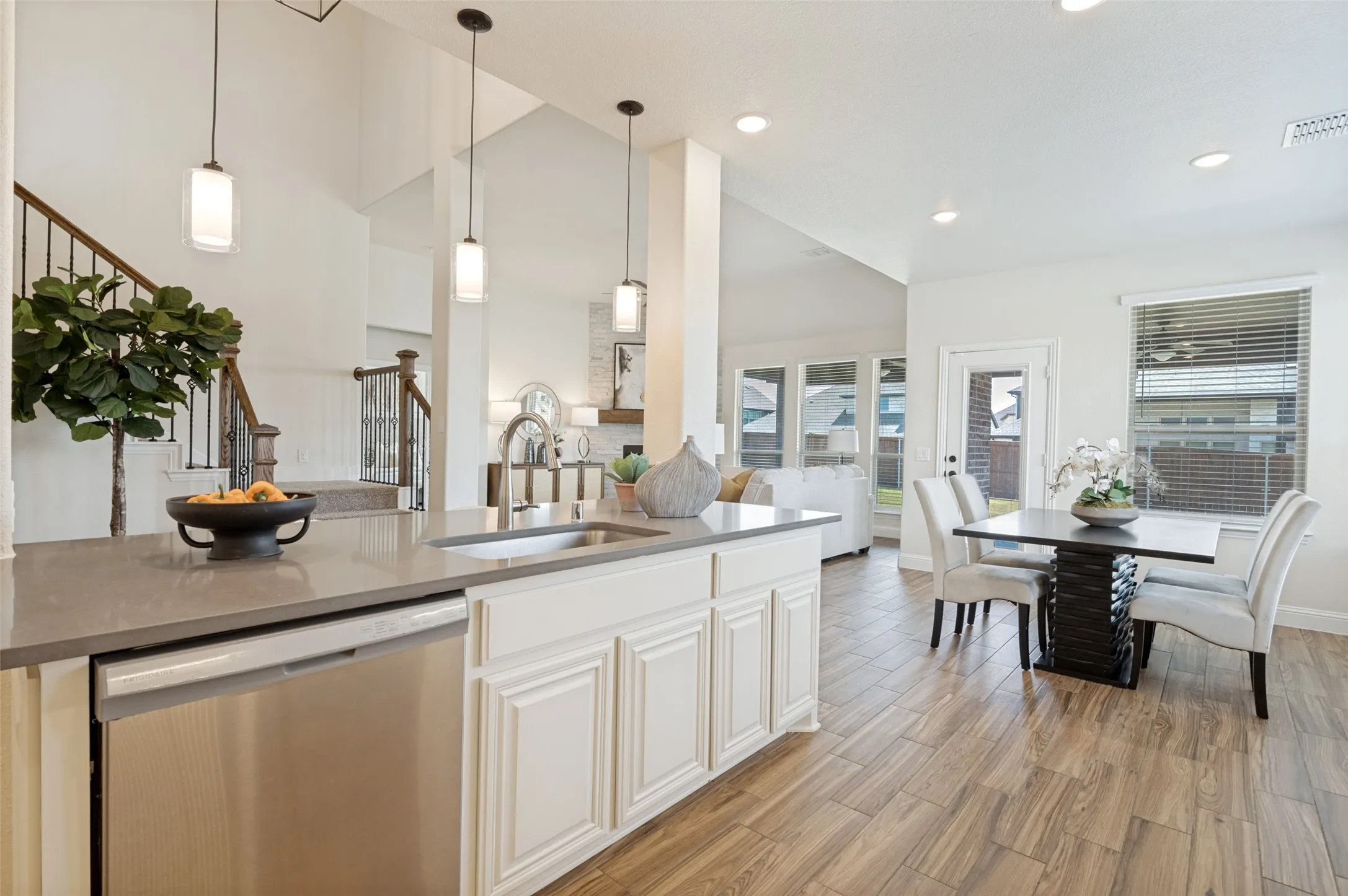 Kitchen island with integrated stainless steel dishwasher, undermount sink, and three pendant lights