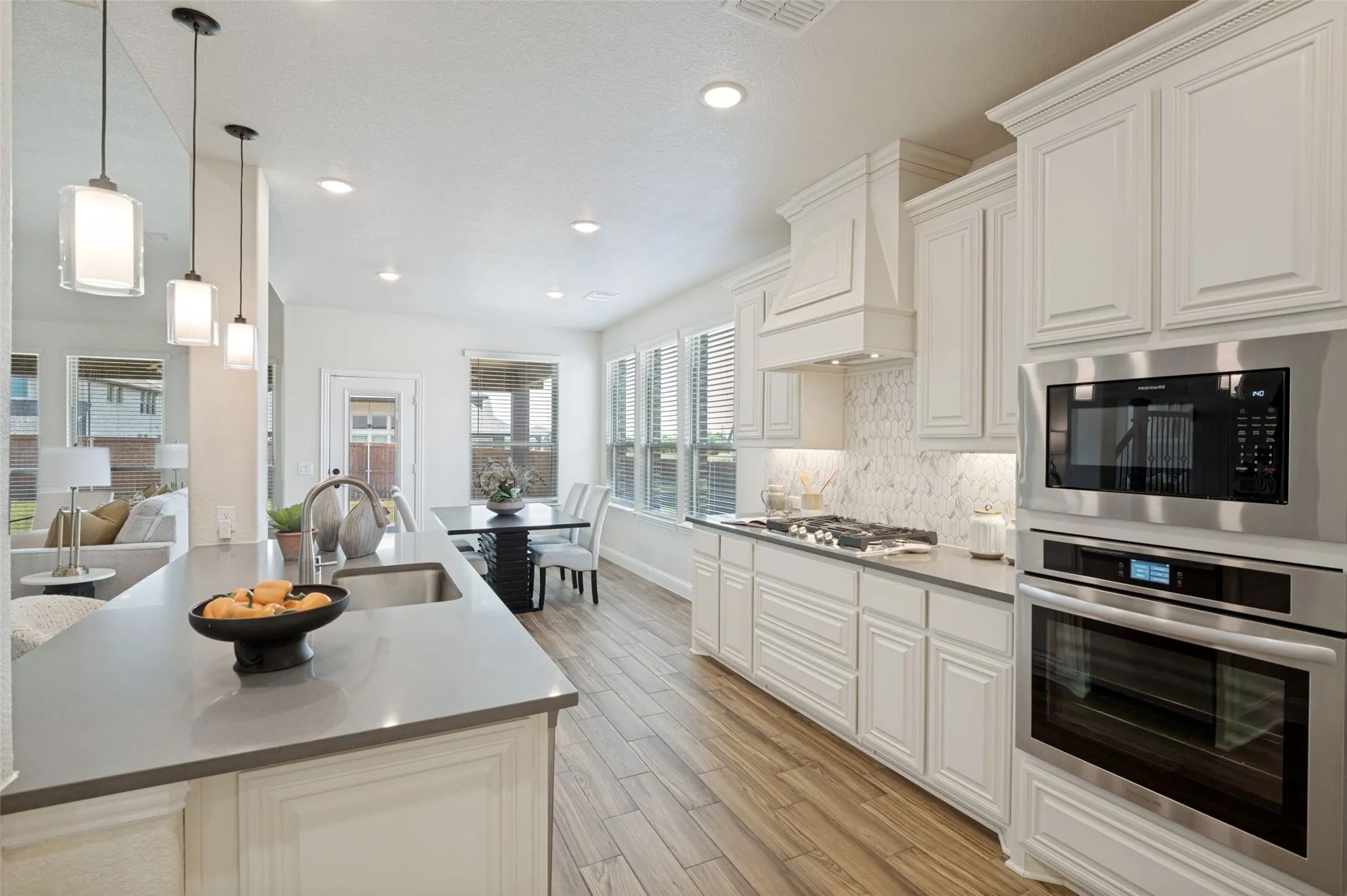 Kitchen featuring white cabinetry, stainless steel appliances, wood-finish flooring, recessed lighting, and a kitchen island with pendant lighting