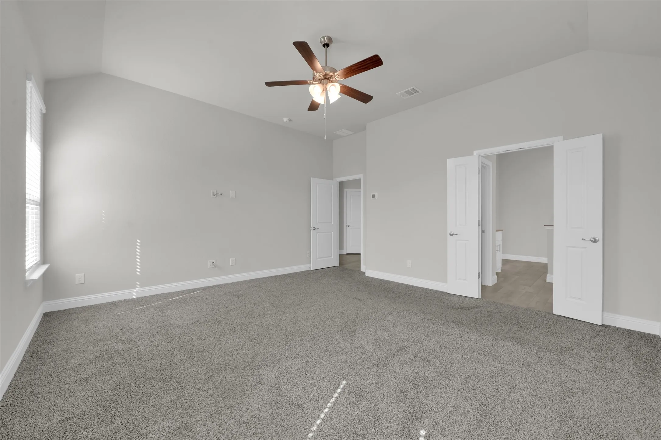 Vaulted ceiling with a ceiling fan, light gray wall paint, gray carpet, and white trim molding