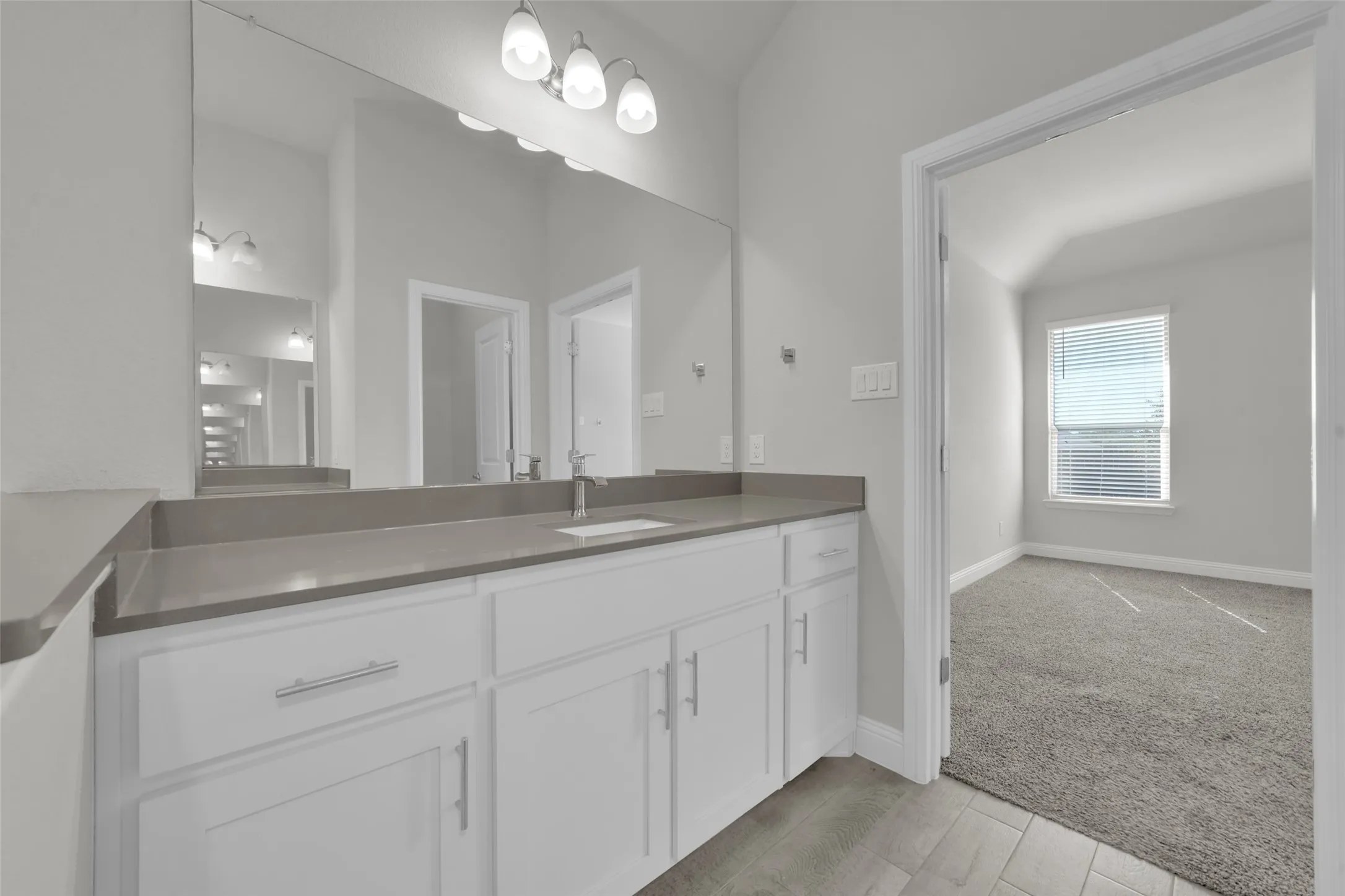 White vanity with ample cabinet storage, a single integrated sink, and a large mirror