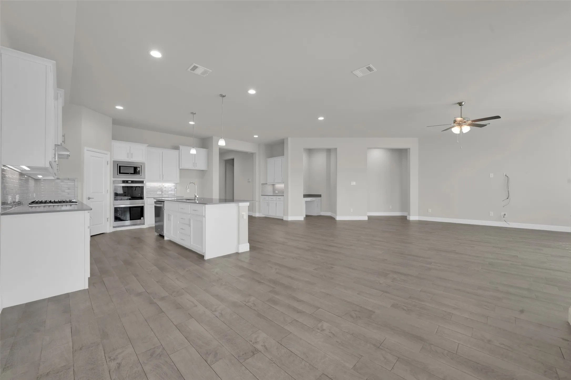 Open-concept living area featuring wood-finish flooring, recessed lighting, and a ceiling fan