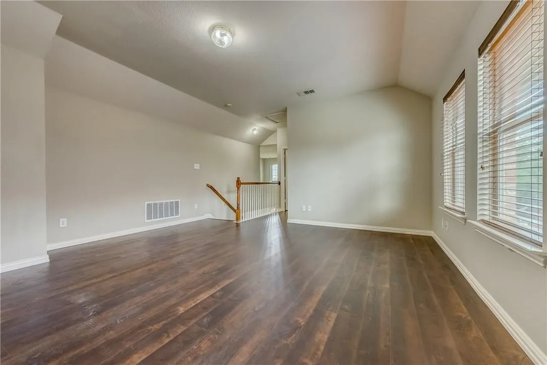 Unfurnished room with dark hardwood / wood-style flooring and vaulted ceiling